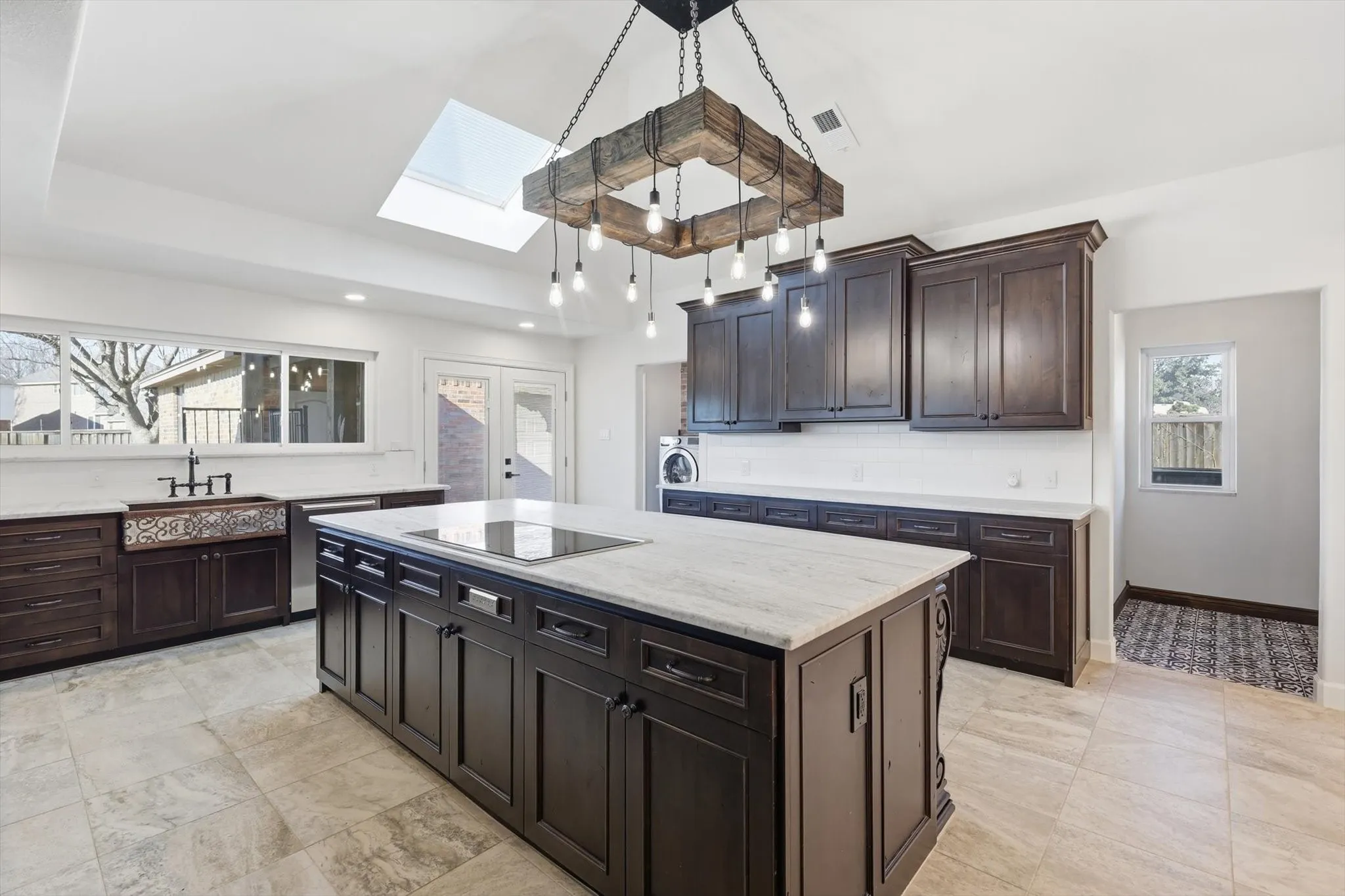 Kitchen featuring a kitchen island, a skylight, dark wood finish cabinets, healthy amount of natural light, and a raised ceiling