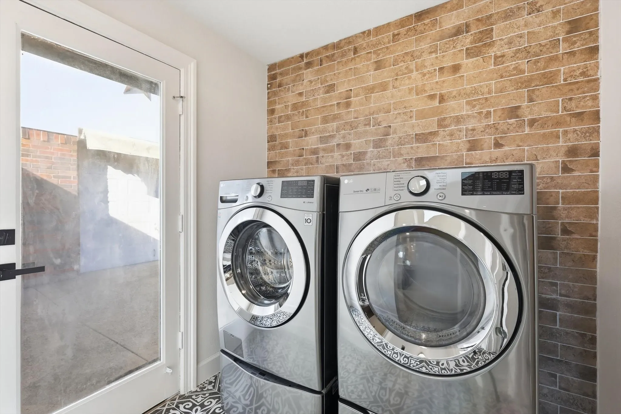 Laundry area with washing machine and dryer and brick wall