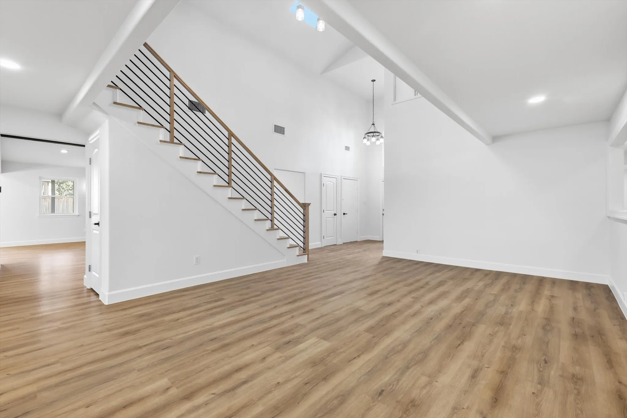 Unfurnished living room with recessed lighting, light wood finished floors, and a high ceiling
