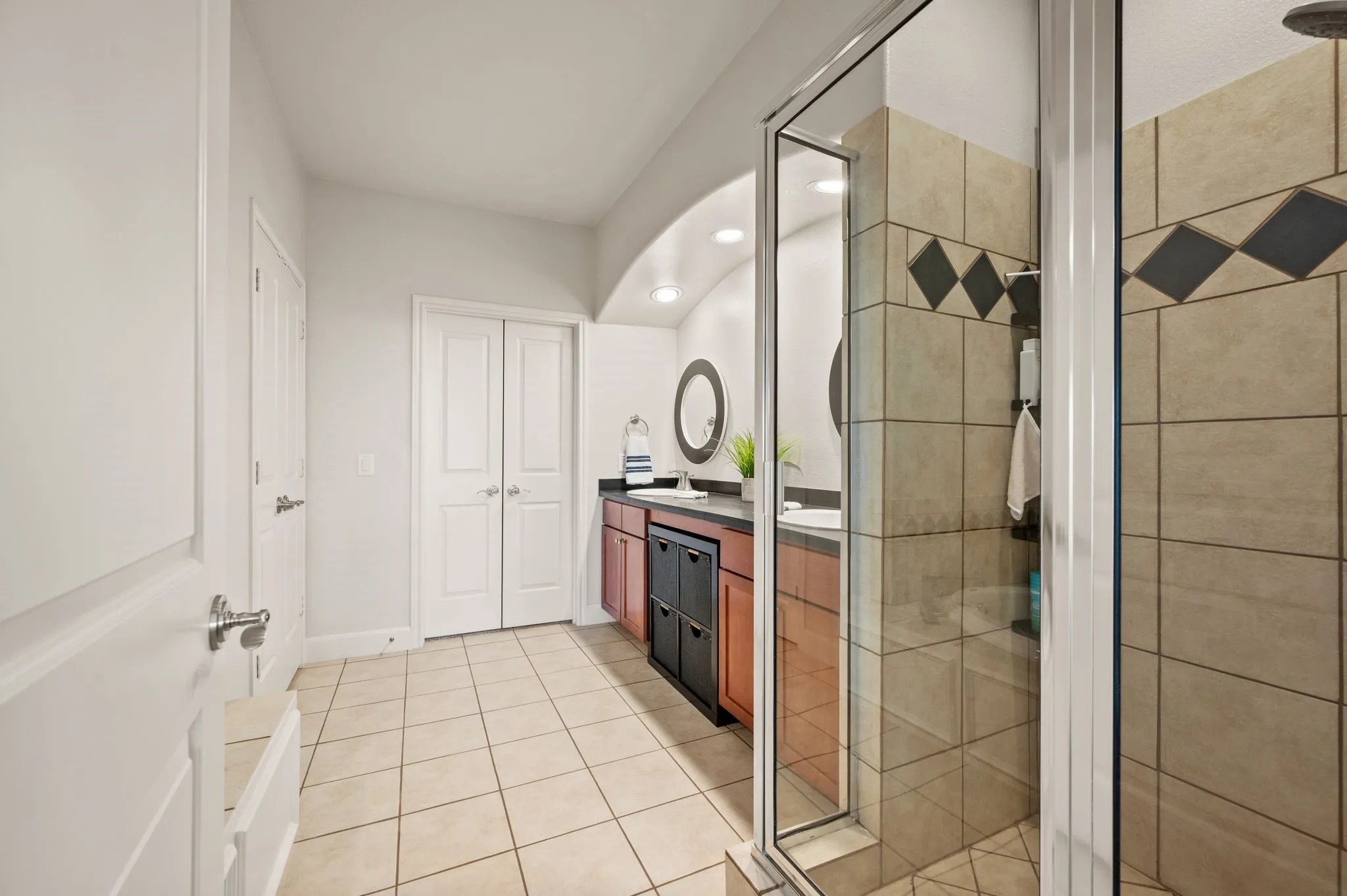 Primary Bathroom featuring double vanity, a shower stall, and light tile patterned floors