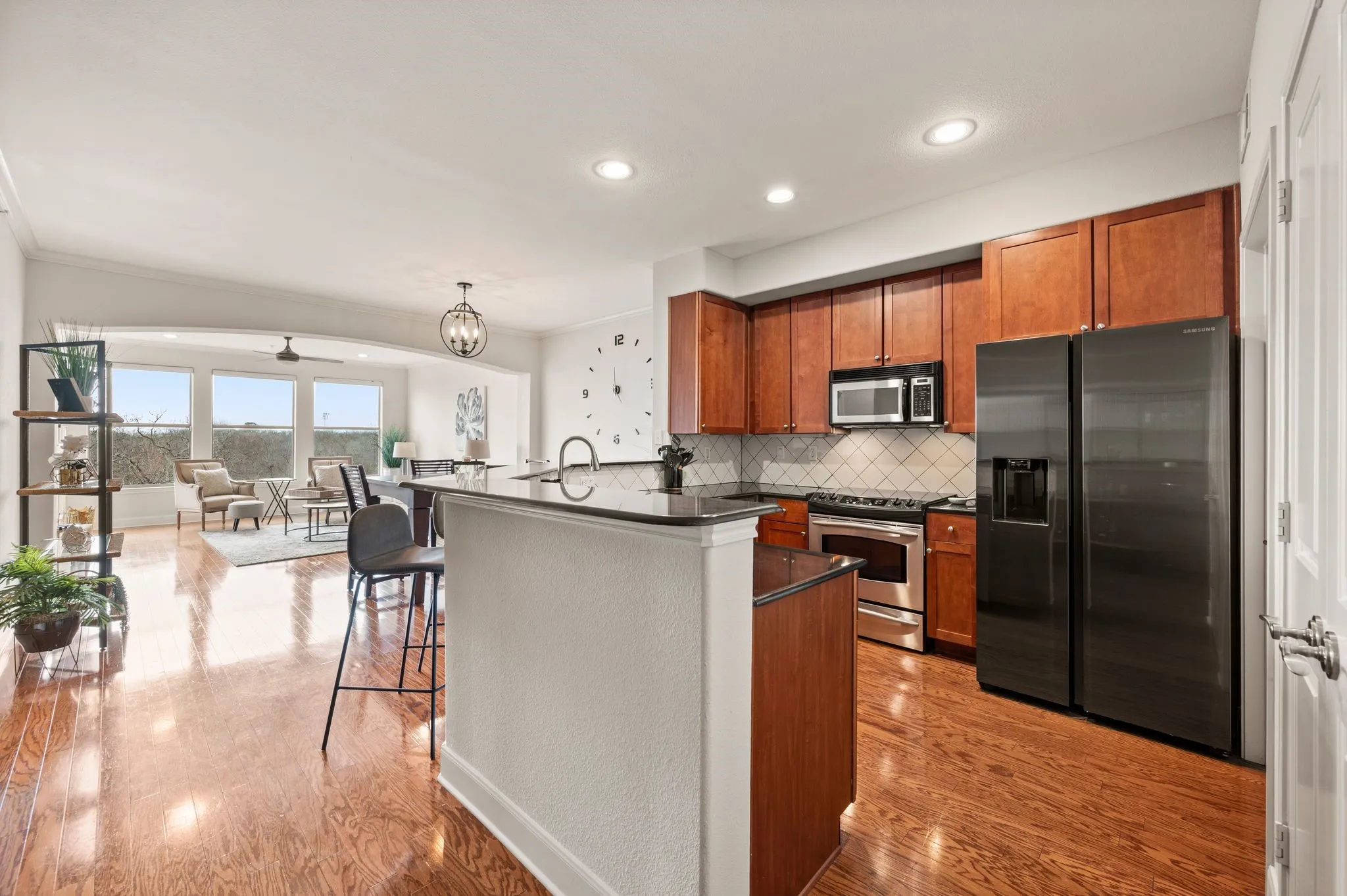 Kitchen with stainless steel appliances, wood finish cabinets, a breakfast bar area, backsplash, and light wood-style floors