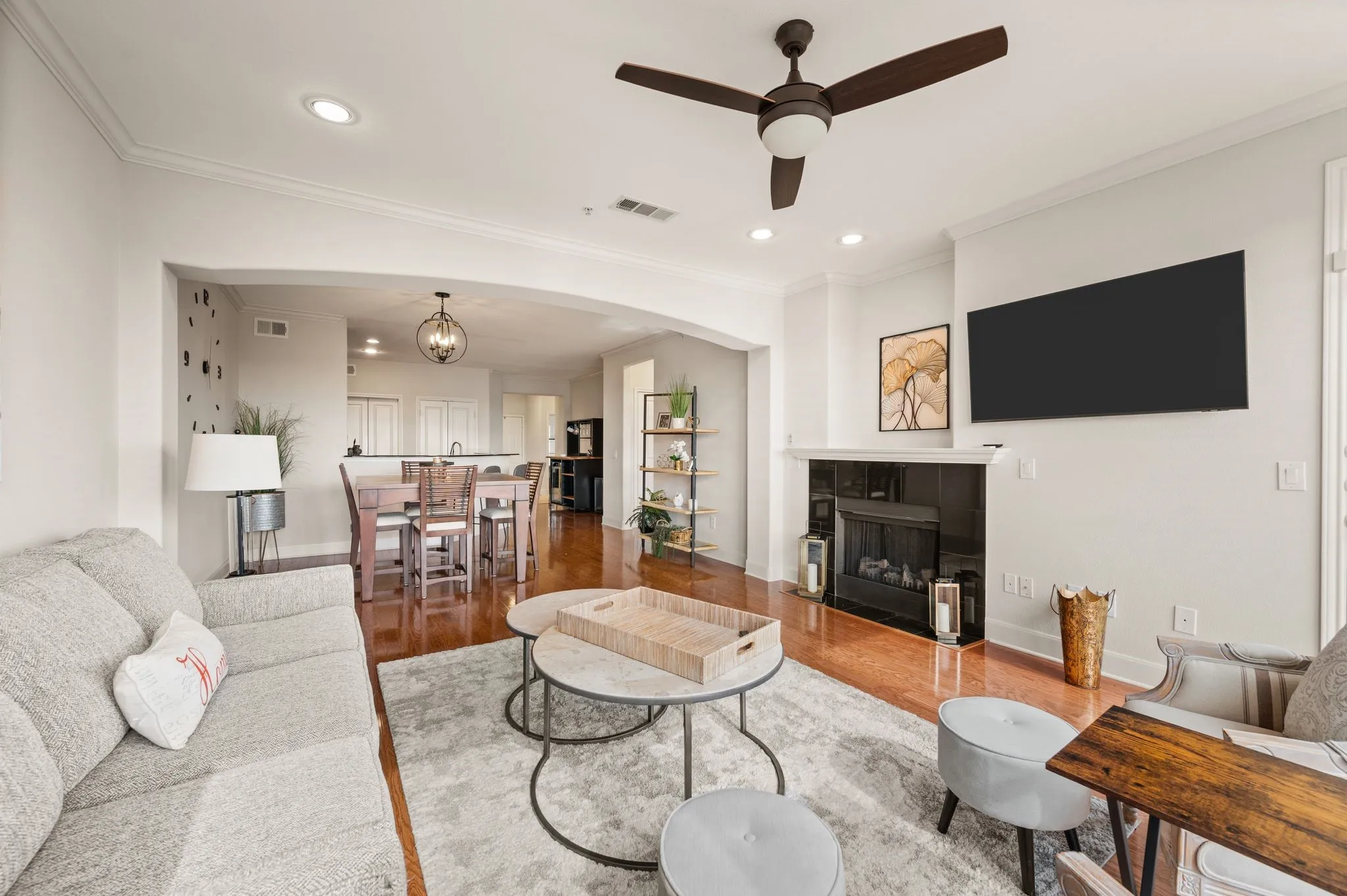 Living area with wood finished floors, ornamental molding, ceiling fan, a fireplace, and a chandelier