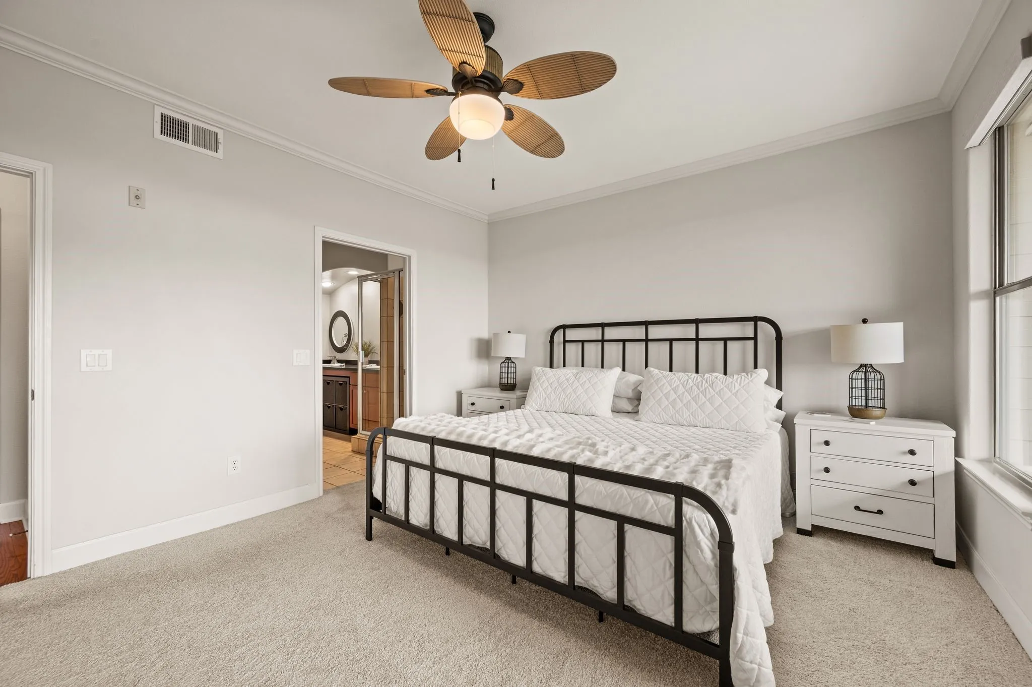 Primary Bedroom featuring ornamental molding, light colored carpet, ceiling fan, and ensuite bathroom
