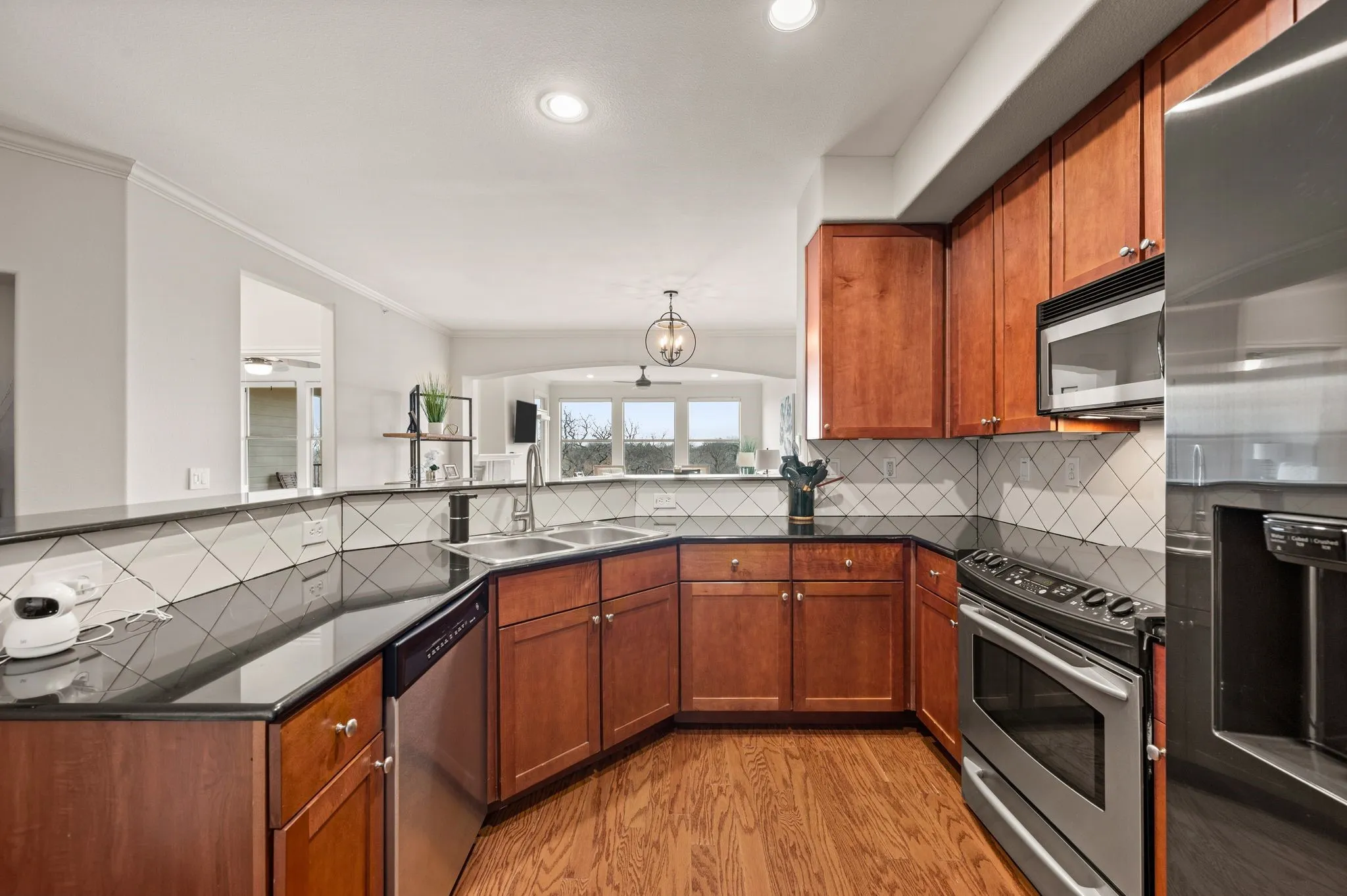 Kitchen with stainless steel appliances, wood finish cabinetry, light wood-style floors, crown molding, and tasteful backsplash