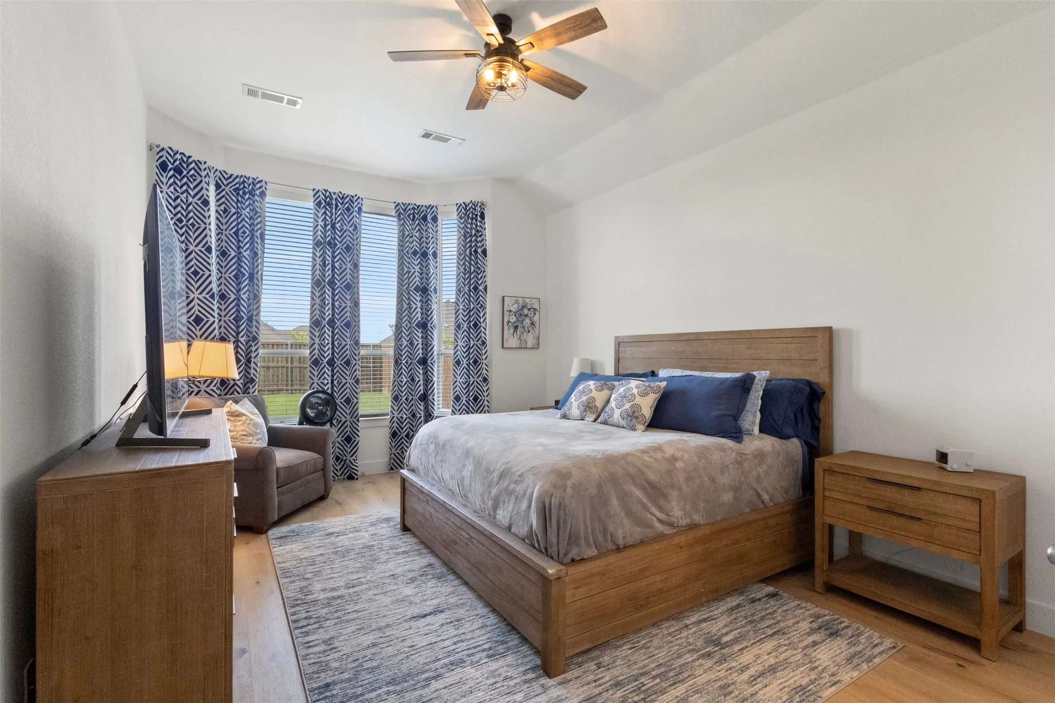 Bedroom with light wood-type flooring, ceiling fan, and vaulted ceiling