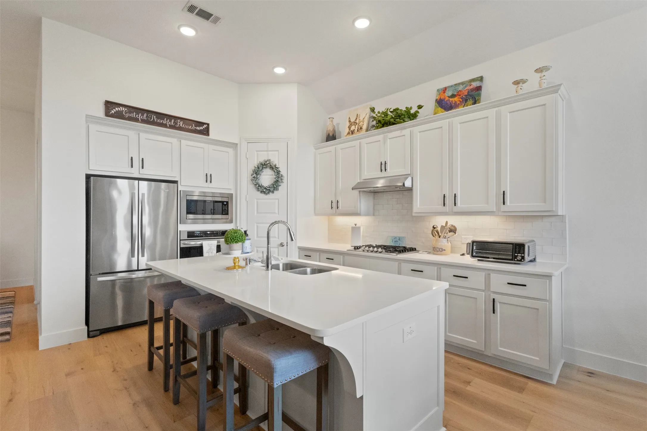 Kitchen featuring stainless steel appliances, decorative backsplash, a kitchen breakfast bar, under cabinet range hood, and recessed lighting