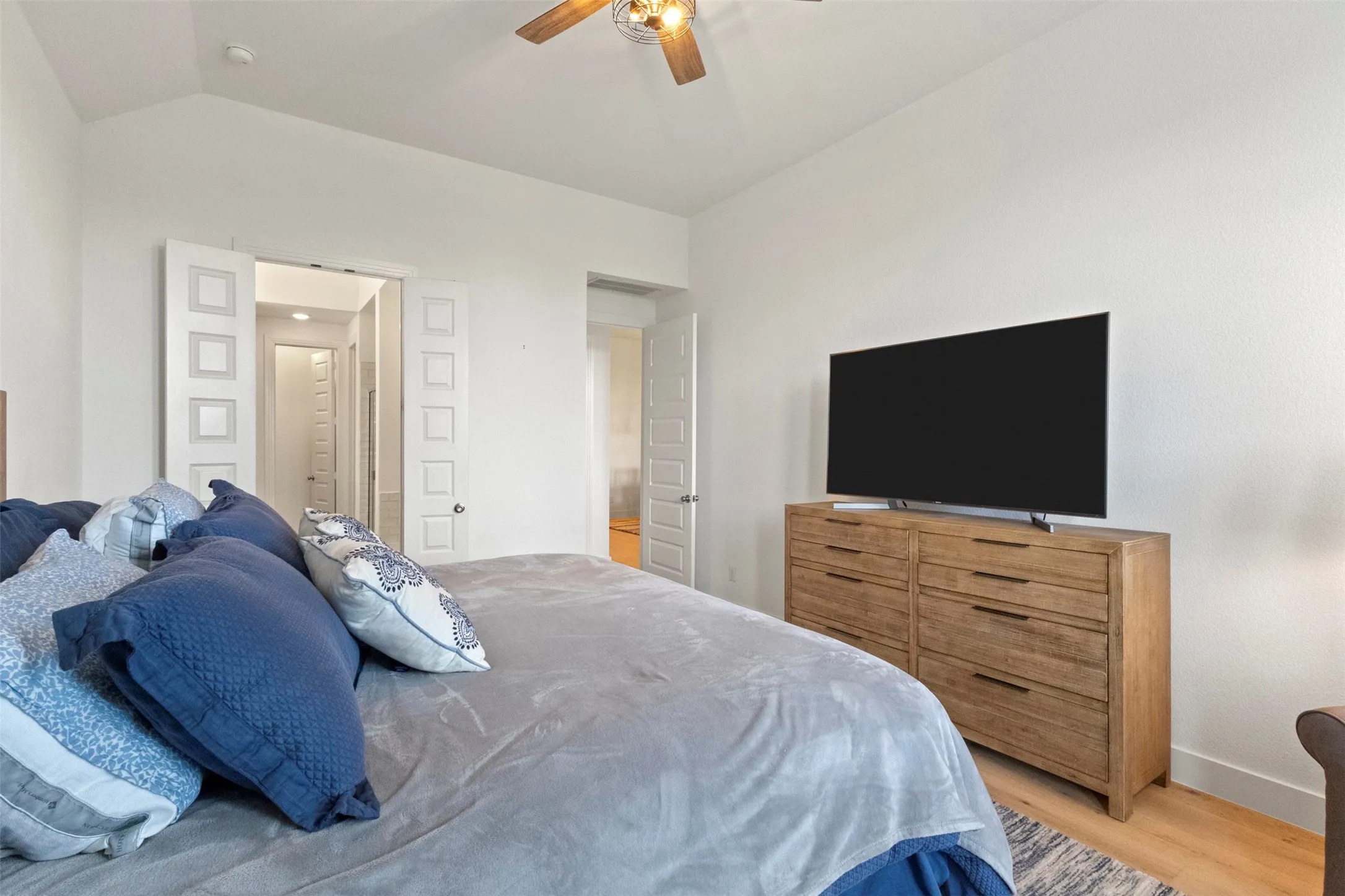 Bedroom featuring light wood-style flooring, vaulted ceiling, and a ceiling fan