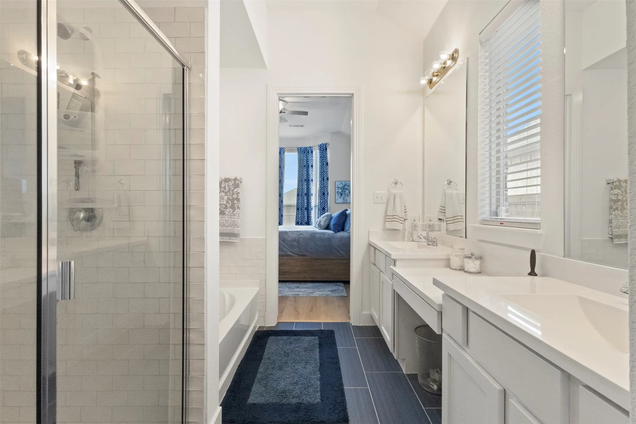Ensuite bathroom with double vanity, a stall shower, healthy amount of natural light, and a bath