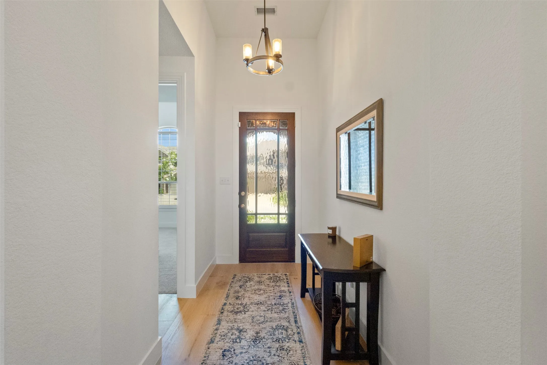 Foyer featuring light wood-style flooring and updated chandelier