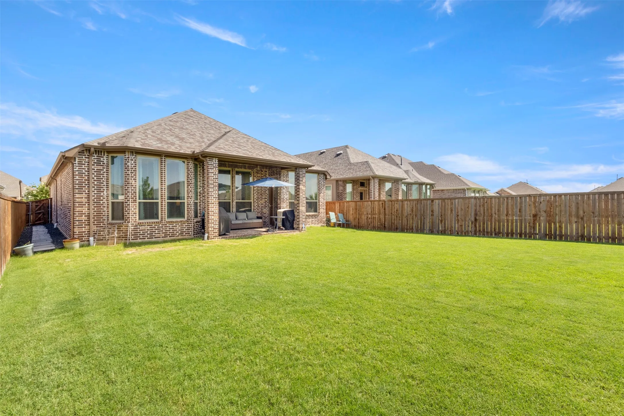 Rear view of property featuring a fenced backyard and brick siding