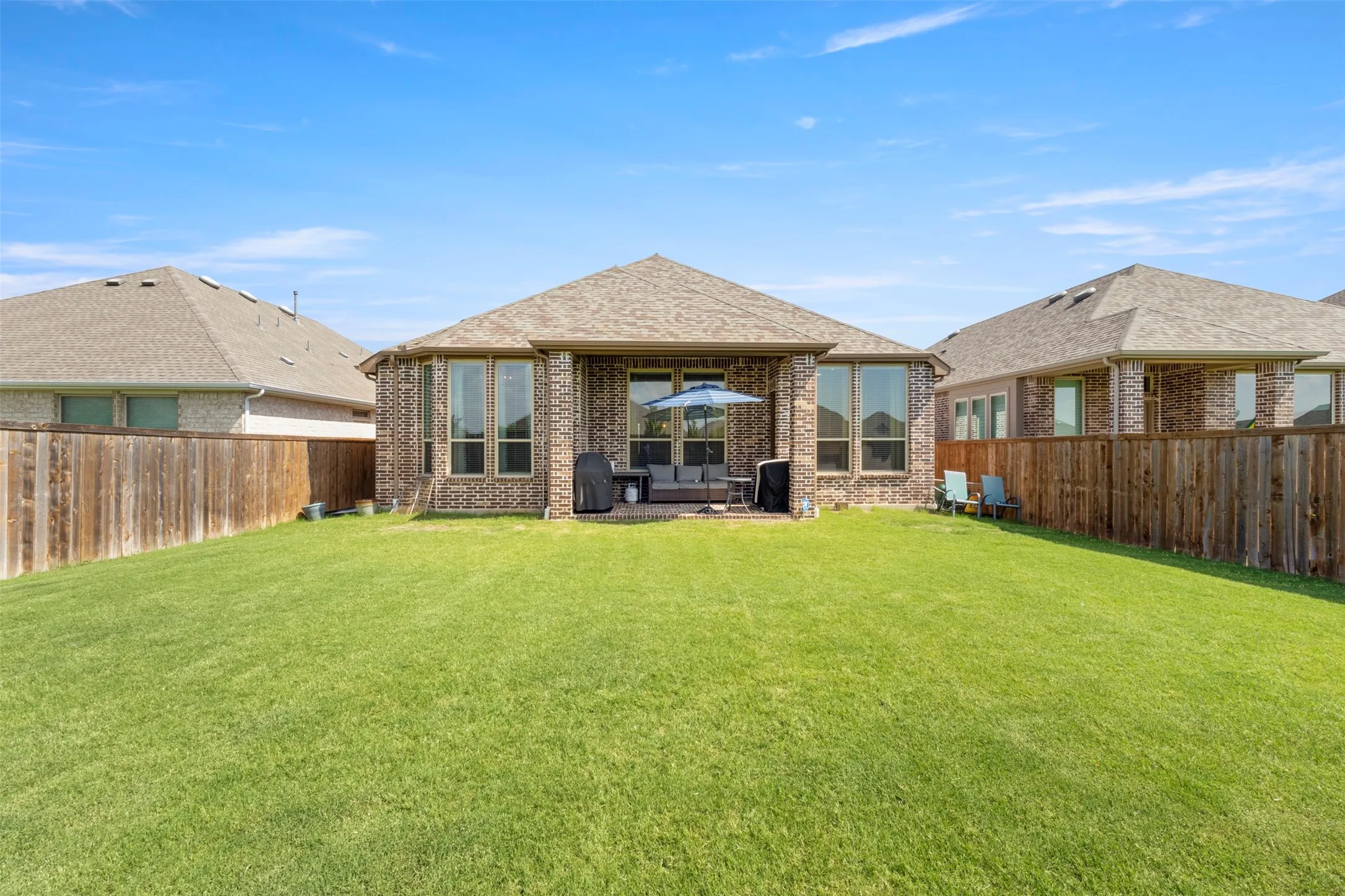 Rear view of house featuring a fenced backyard and brick siding