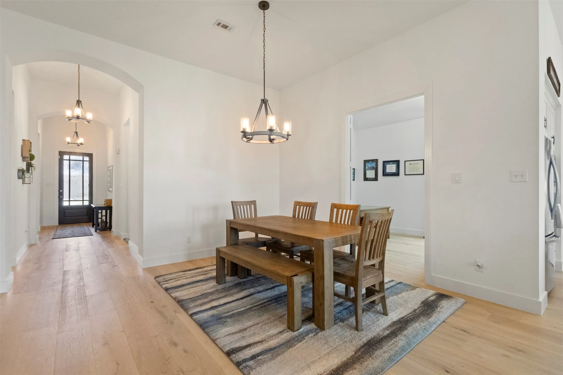 Dining room featuring arched walkways, a chandelier, and light wood-style flooring