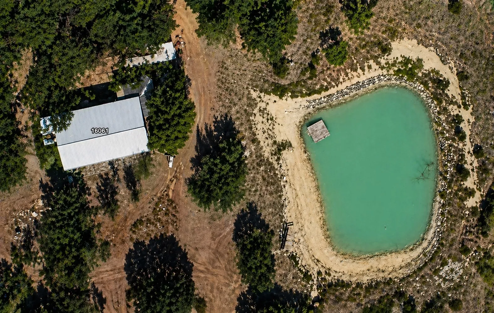 Property featuring a private pond with a floating dock, bordered by a natural rock wall