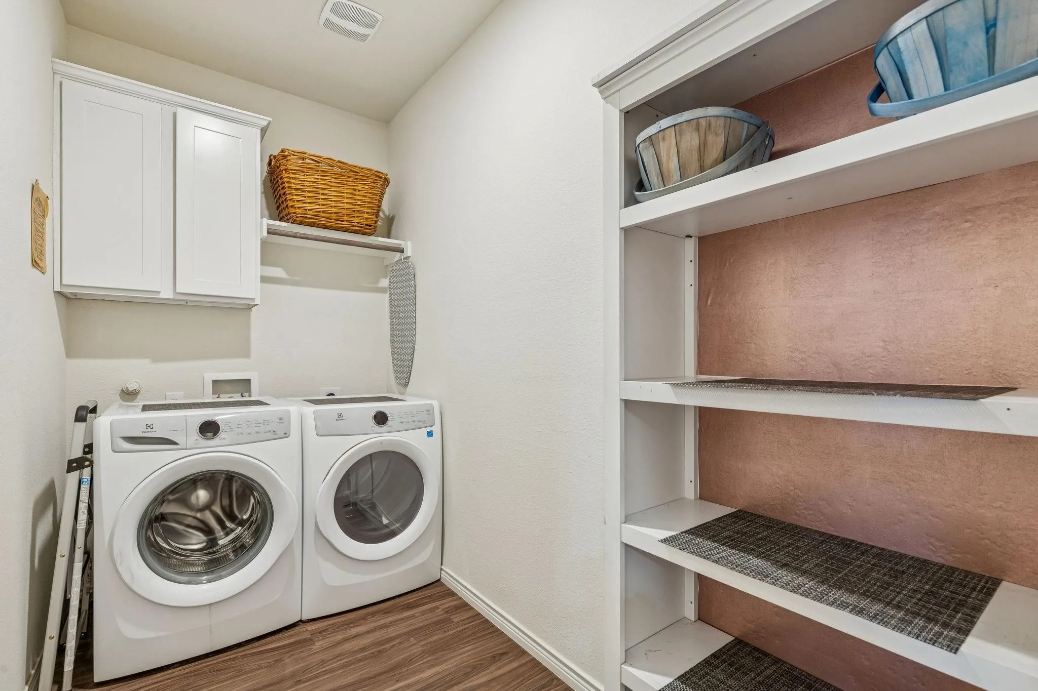 Dedicated laundry space featuring wood-finish flooring