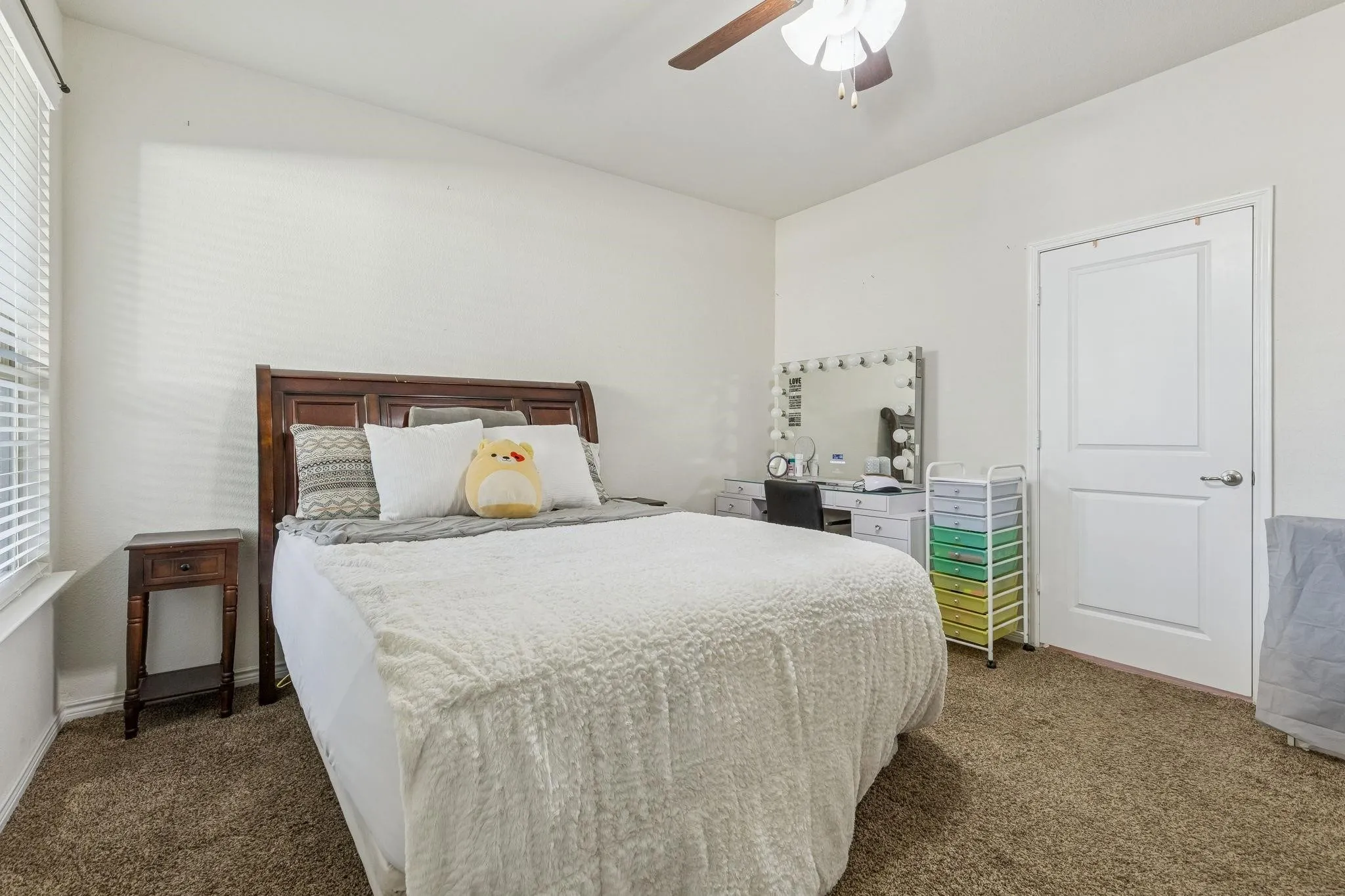 Neutral wall paint, brown carpeting, and a ceiling fan with light fixture