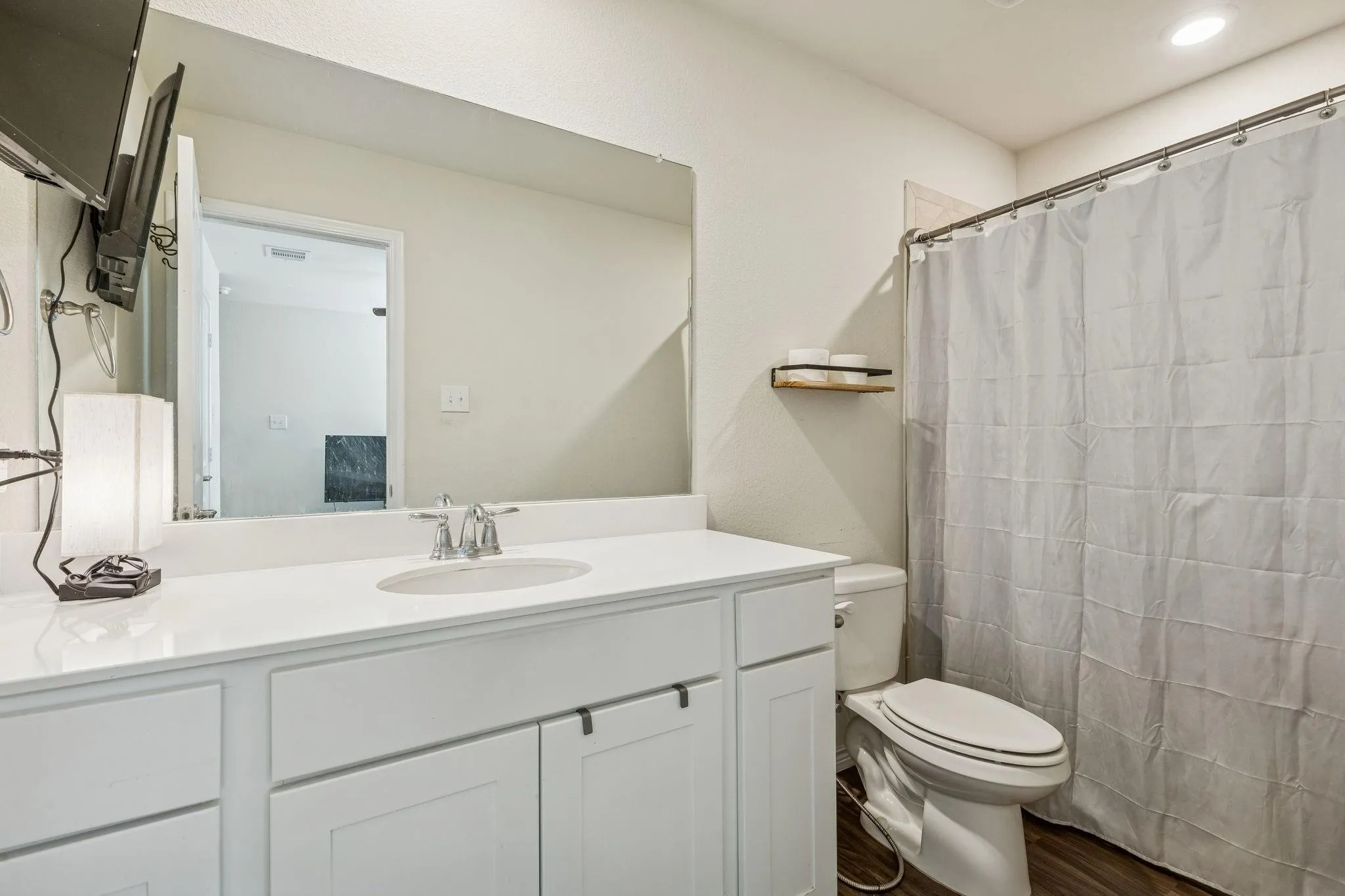 Guest bathroom is ensuite White vanity with a single undermount sink, a chrome faucet, and a large wall-mounted mirror