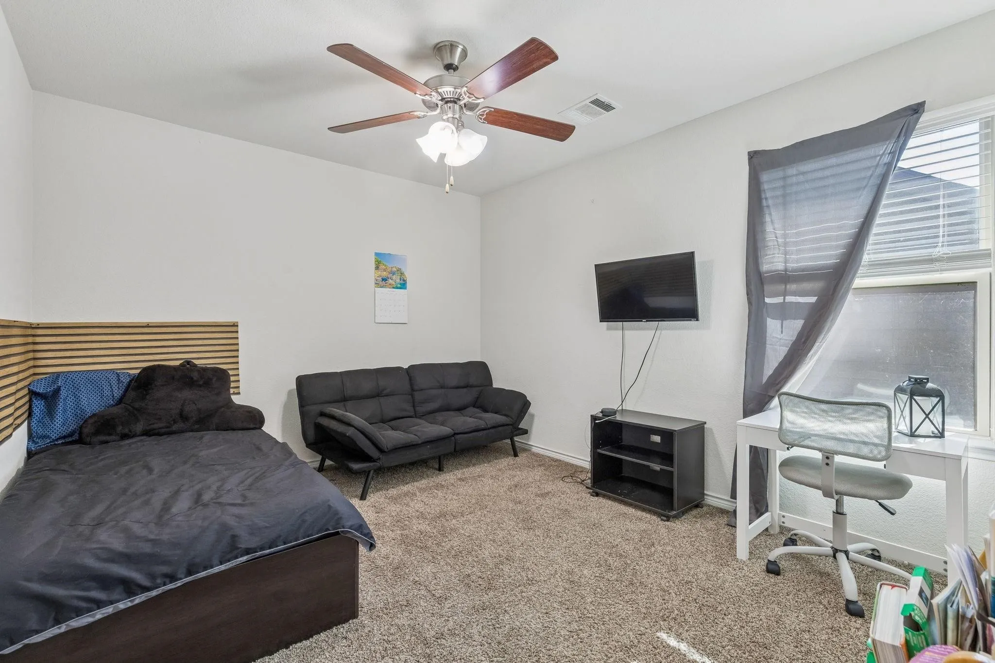 Carpeted room featuring a ceiling fan with light fixture, a window with horizontal blinds, and white walls
