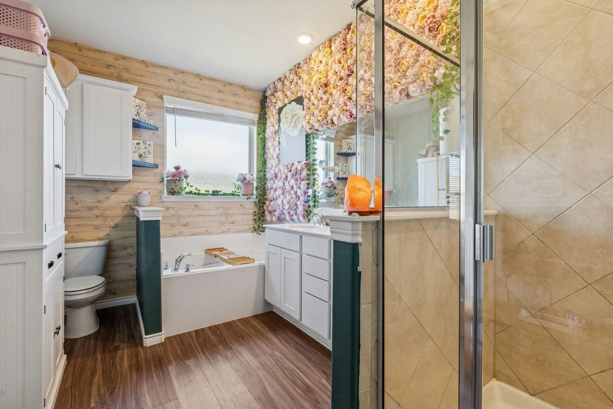 Bathroom featuring a built-in tub, wood-finish flooring, and a glass-enclosed shower