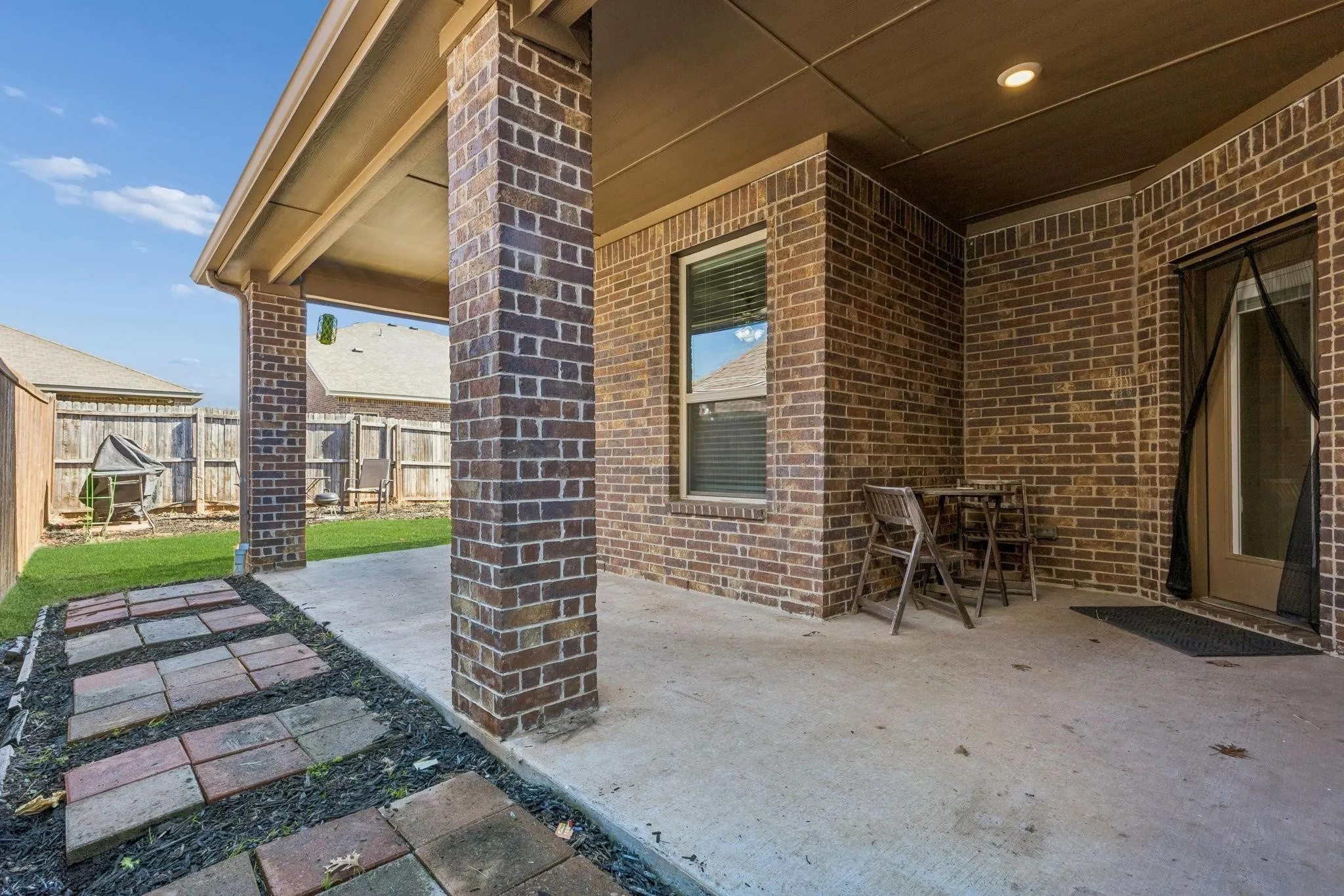 Covered outdoor patio featuring brick pillars, a concrete surface, and recessed lighting