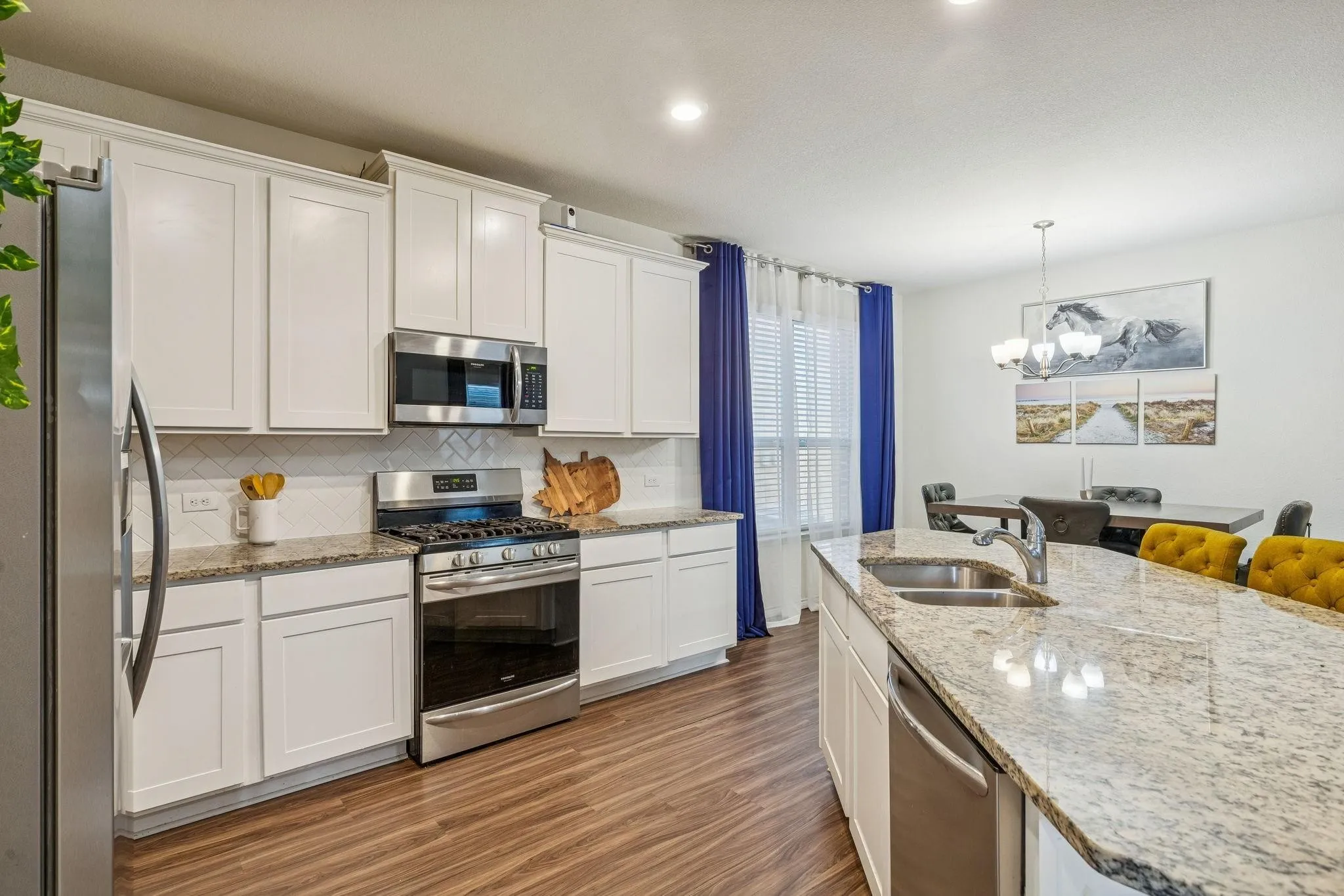 Kitchen featuring white shaker-style cabinetry, stainless steel appliances, speckled stone countertops, and wood-finish flooring