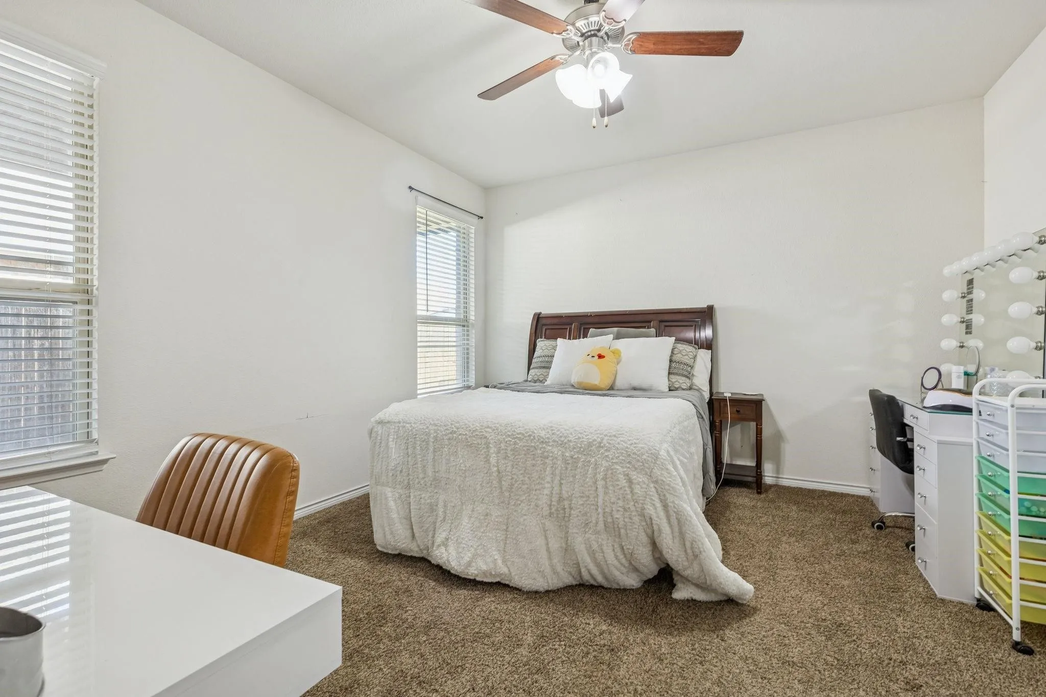 Carpeted room featuring two windows with horizontal blinds, a ceiling fan with light fixture, and white walls