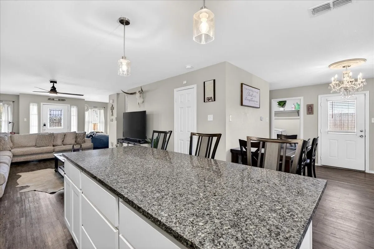 Kitchen boasts of white cabinets, granite countertops, island, stainless style appliances open to the living room
