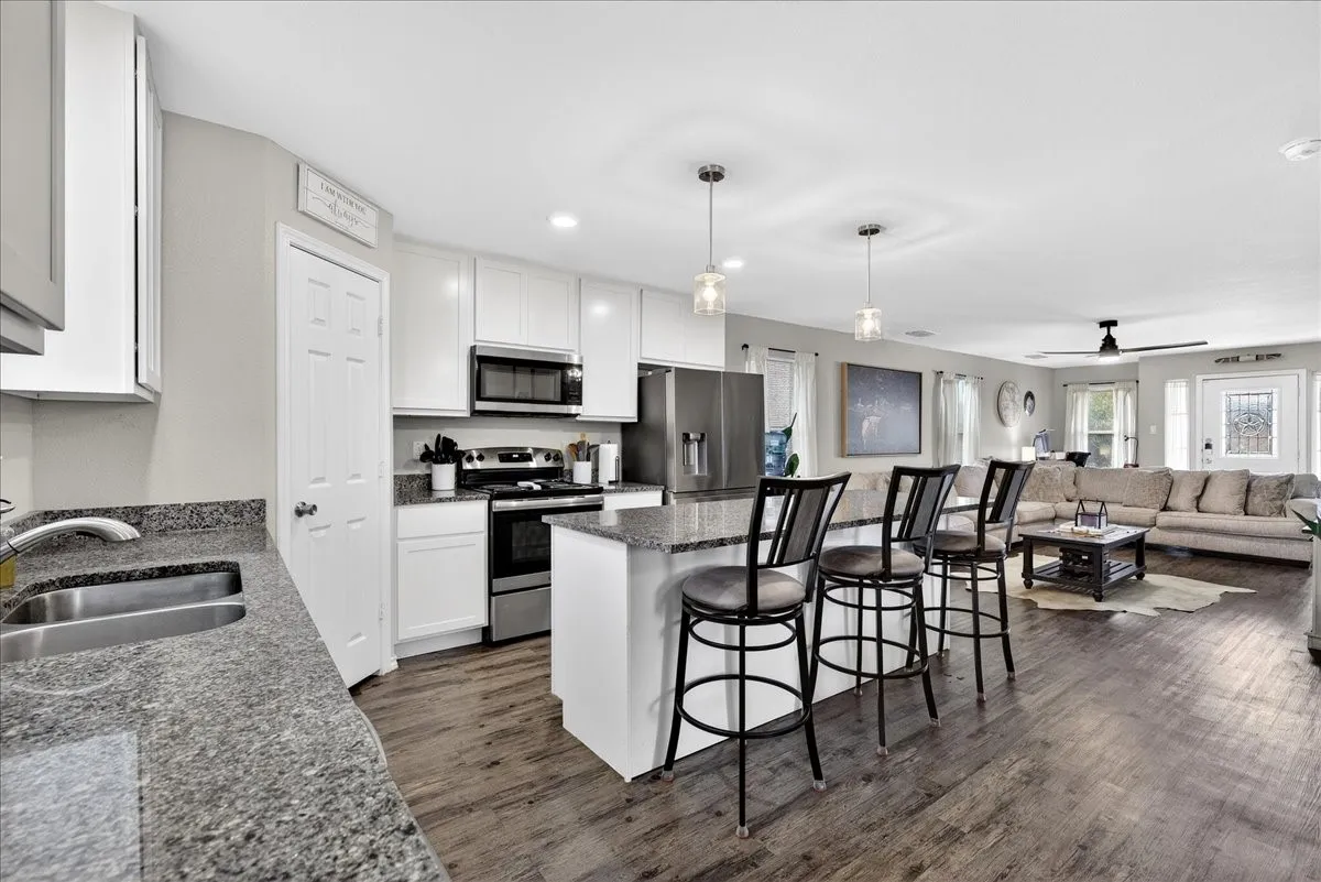 Kitchen boasts of white cabinets, granite countertops, island, stainless style appliances open to the living room