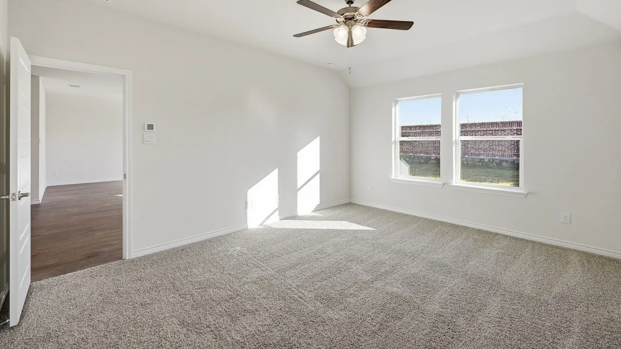 Carpeted empty room with lofted ceiling and a ceiling fan