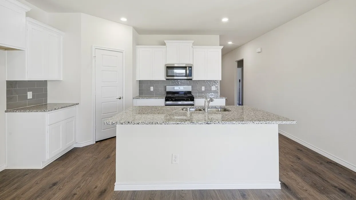 Kitchen featuring light stone counters, stainless steel appliances, backsplash, a center island with sink, and recessed lighting