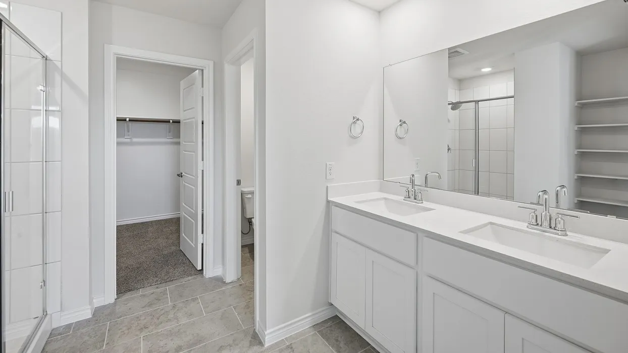 Bathroom featuring a spacious closet, double vanity, and a stall shower
