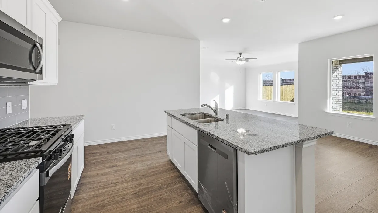 Kitchen with a center island with sink, stainless steel appliances, white cabinets, light stone counters, and recessed lighting