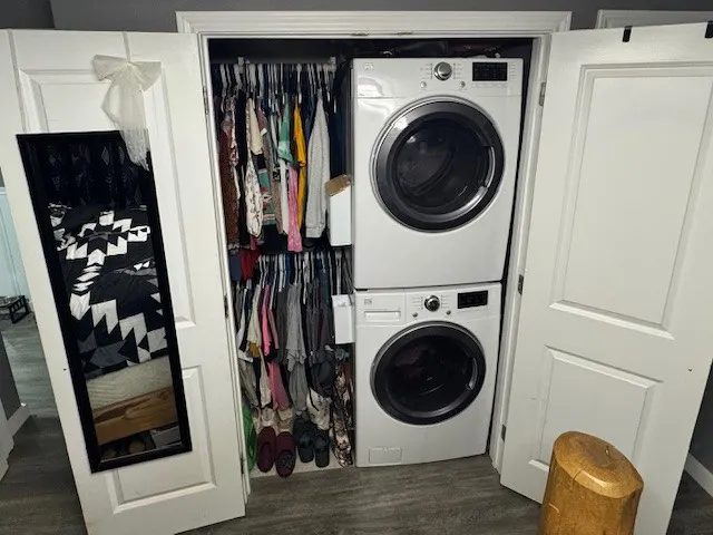 Closet and Laundry area featuring stacked washer and clothes dryer and dark wood finished floors