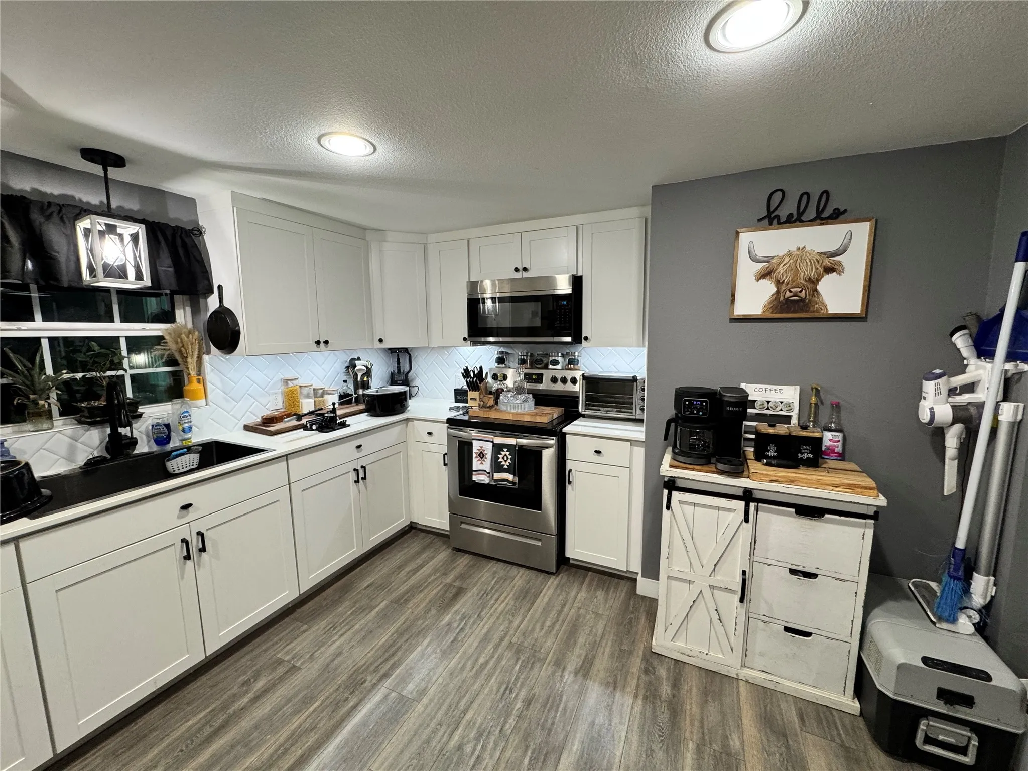 Kitchen with white cabinetry, light countertops, stainless steel appliances, dark wood-style flooring