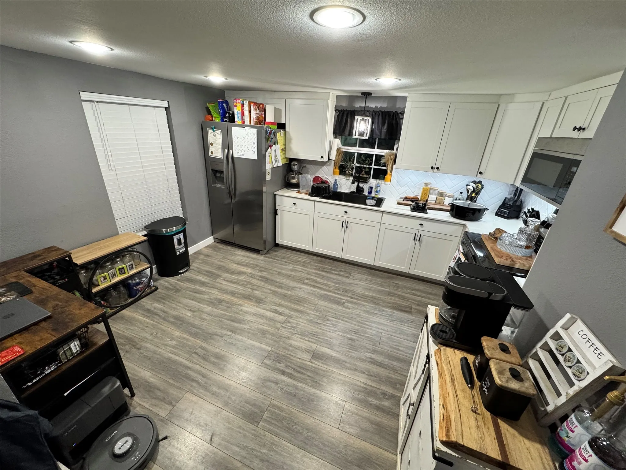 Kitchen featuring white cabinetry, stainless steel, light countertops, and decorative backsplash