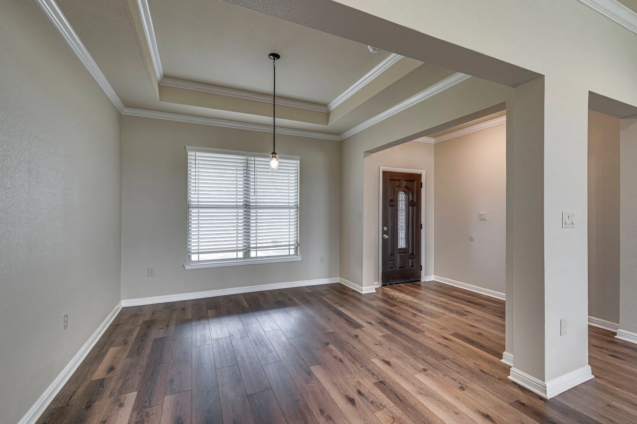 Foyer with ornamental molding, dark wood finished floors, and a tray ceiling