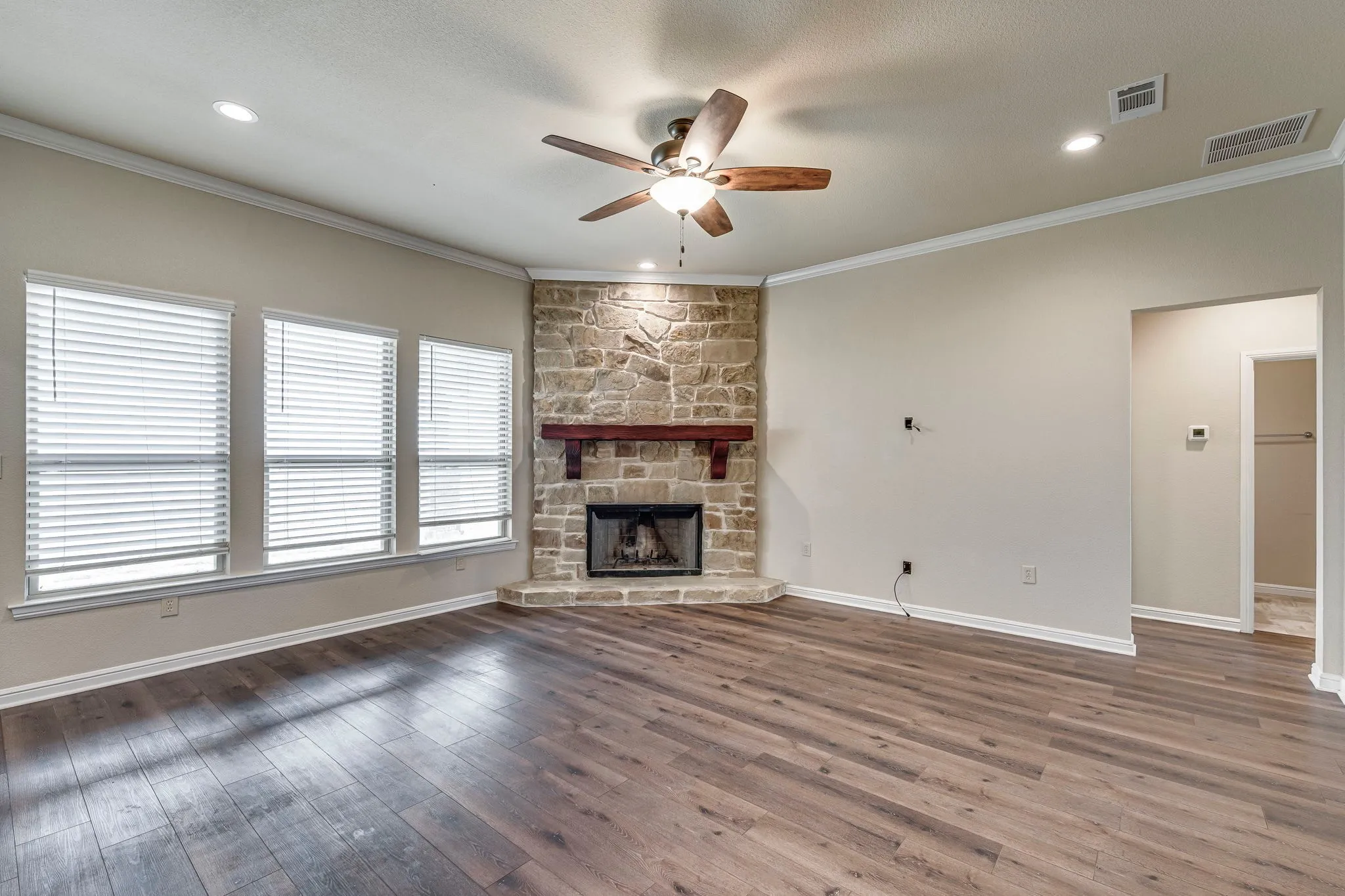 Unfurnished living room with ceiling fan, a fireplace, dark wood finished floors, crown molding, and recessed lighting