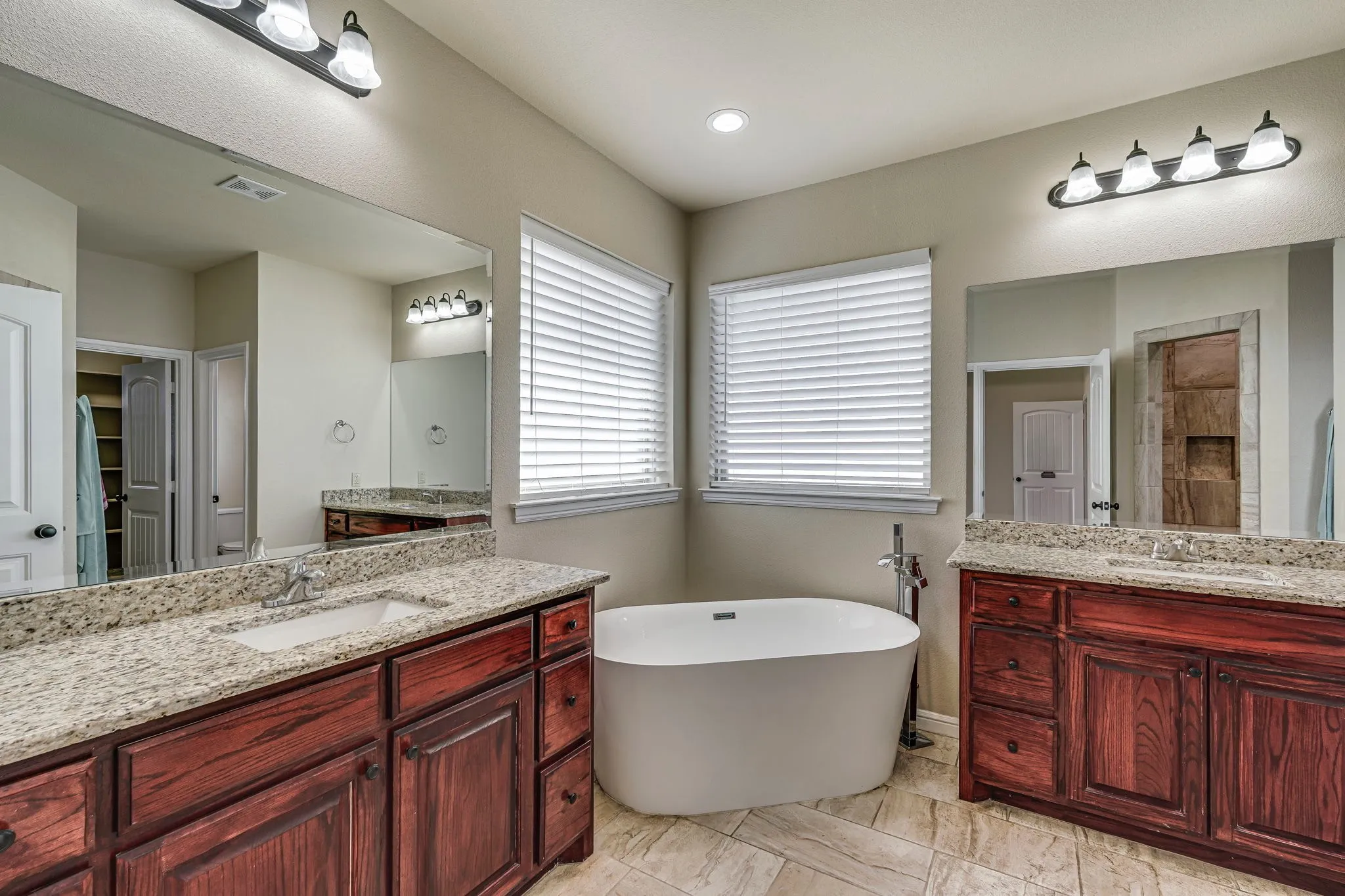 Bathroom featuring two vanities and a soaking tub