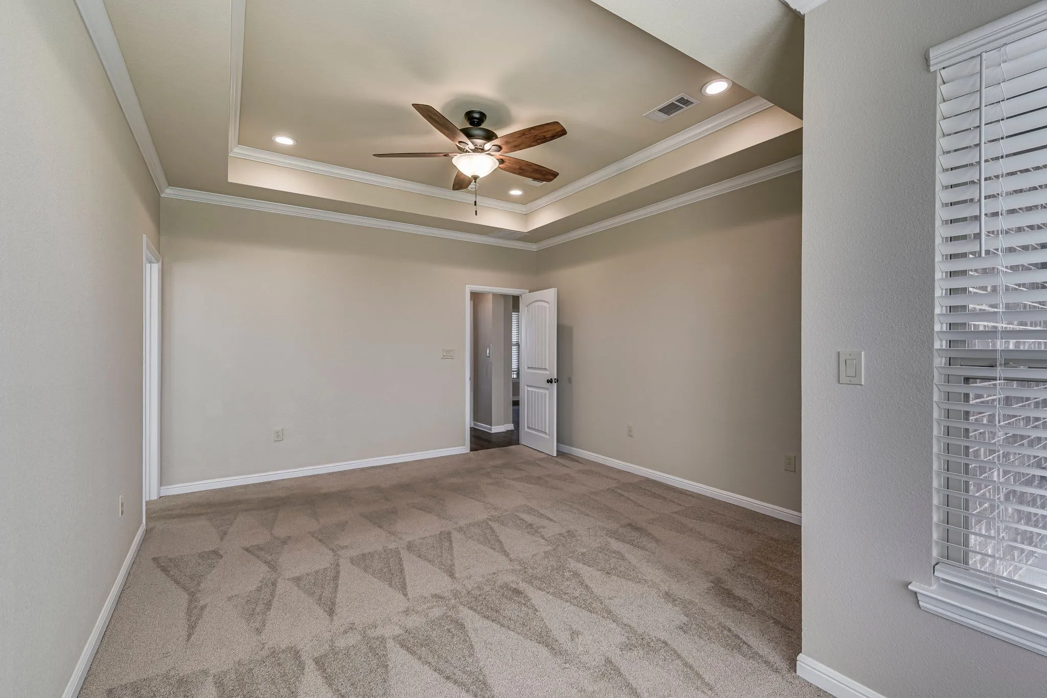 Empty room with ceiling fan, light colored carpet, recessed lighting, a tray ceiling, and ornamental molding