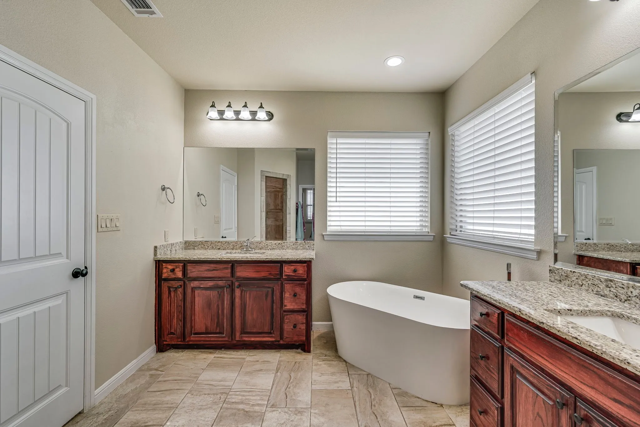 Full bathroom featuring two vanities and a freestanding bath