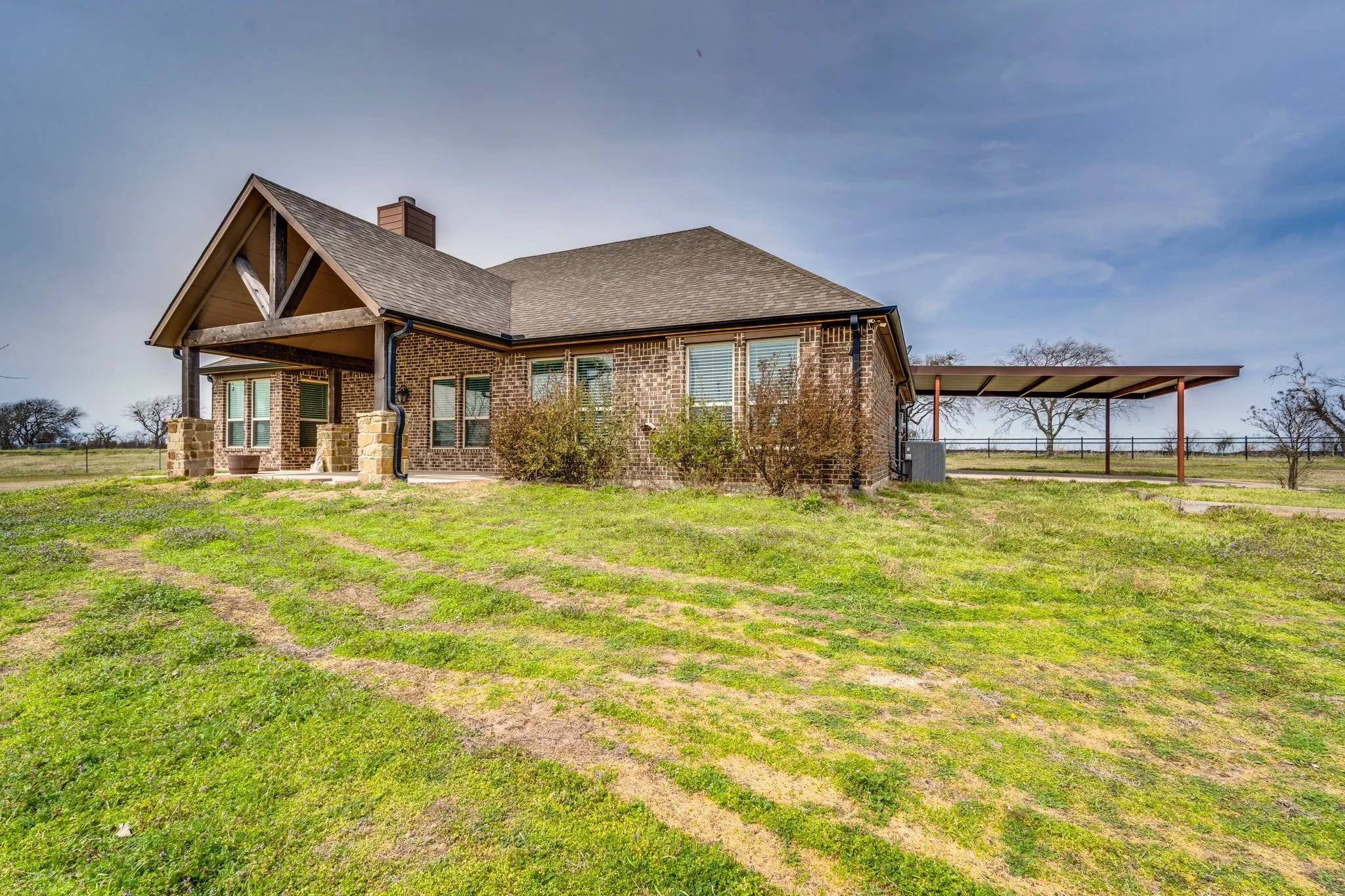 Back of property featuring brick siding, a patio area, a chimney, and roof with shingles