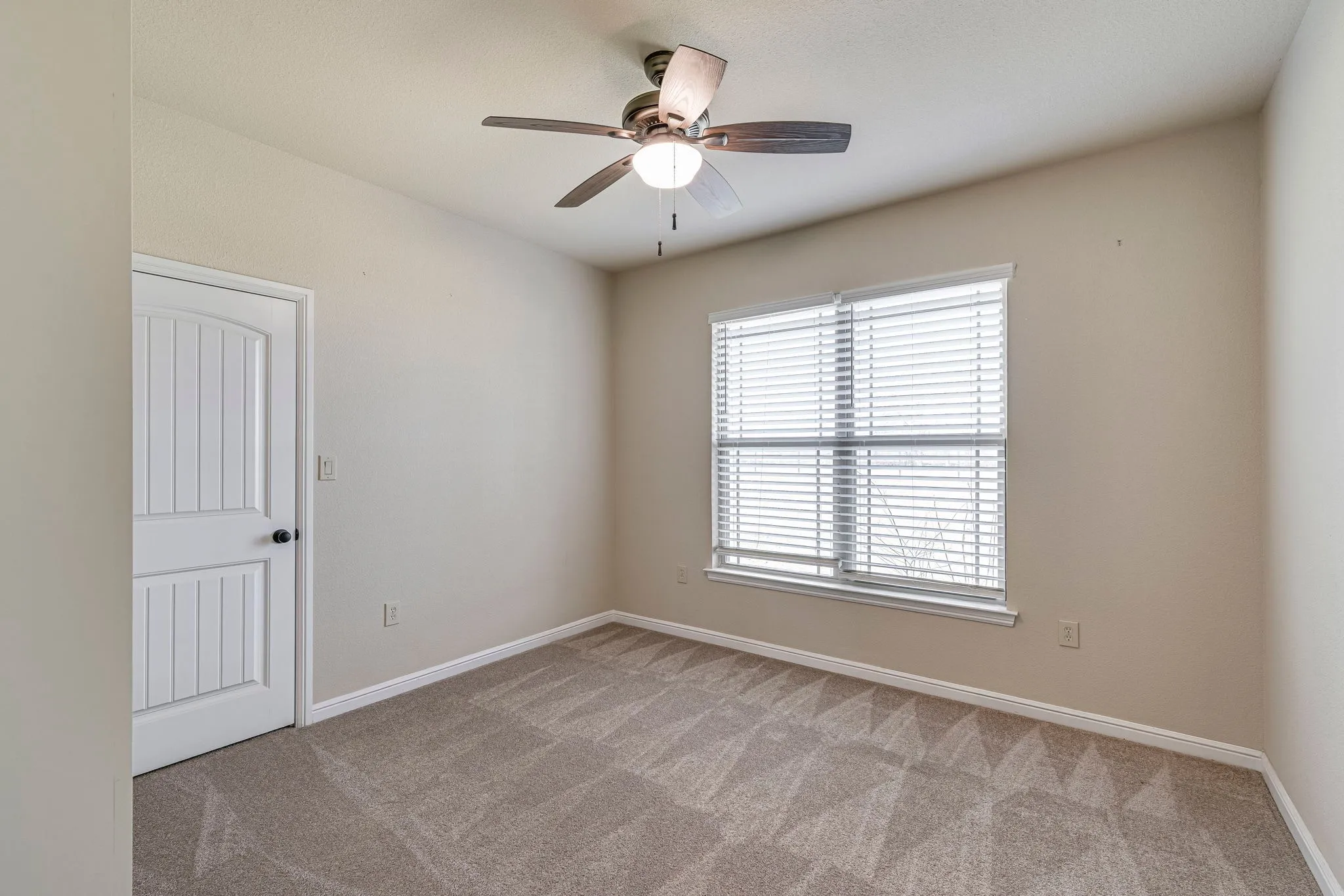 Spare room with a ceiling fan and light carpet