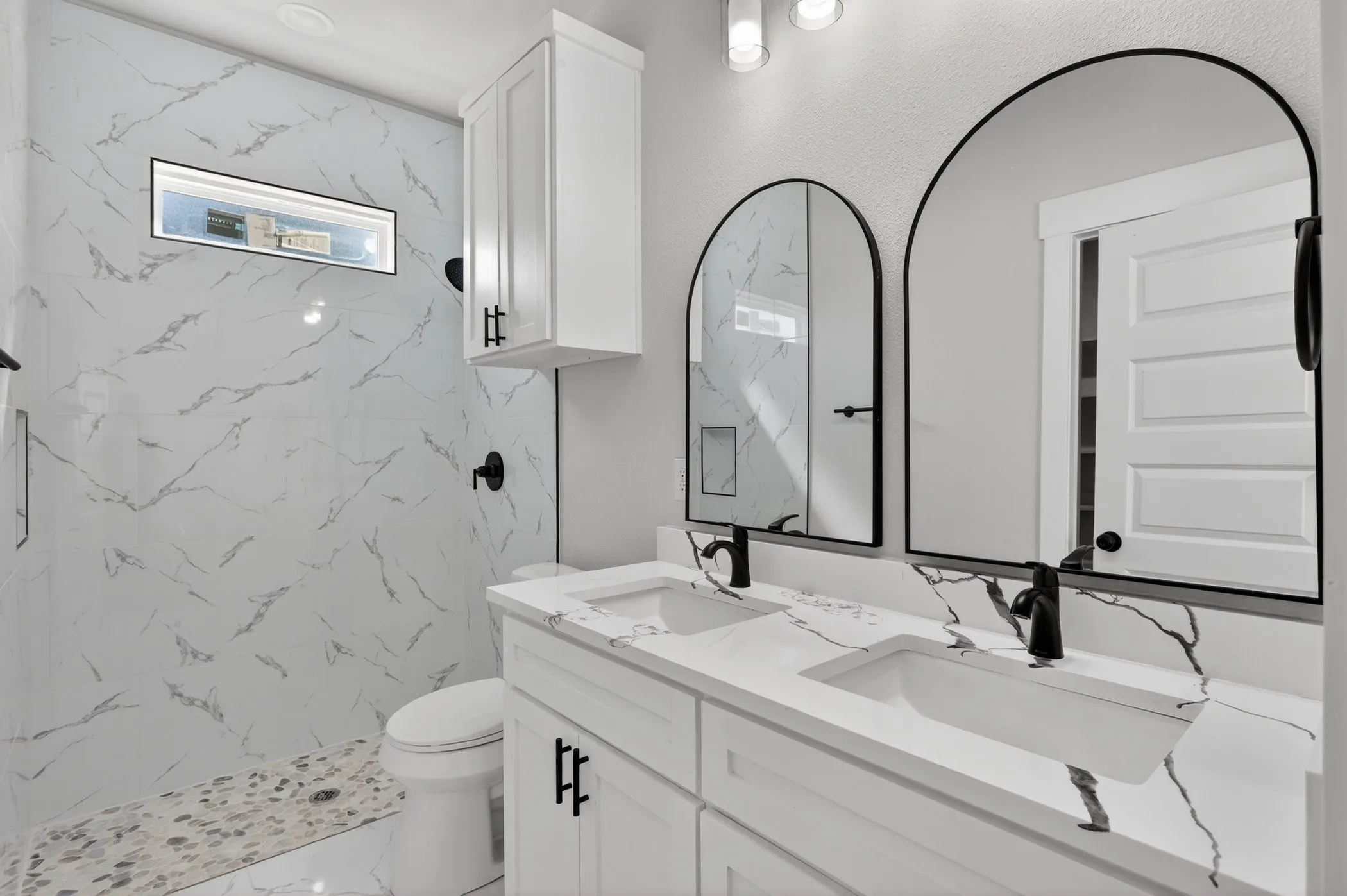 Dual vanity featuring white cabinetry, integrated sinks, and stone-finish countertops with pronounced veining