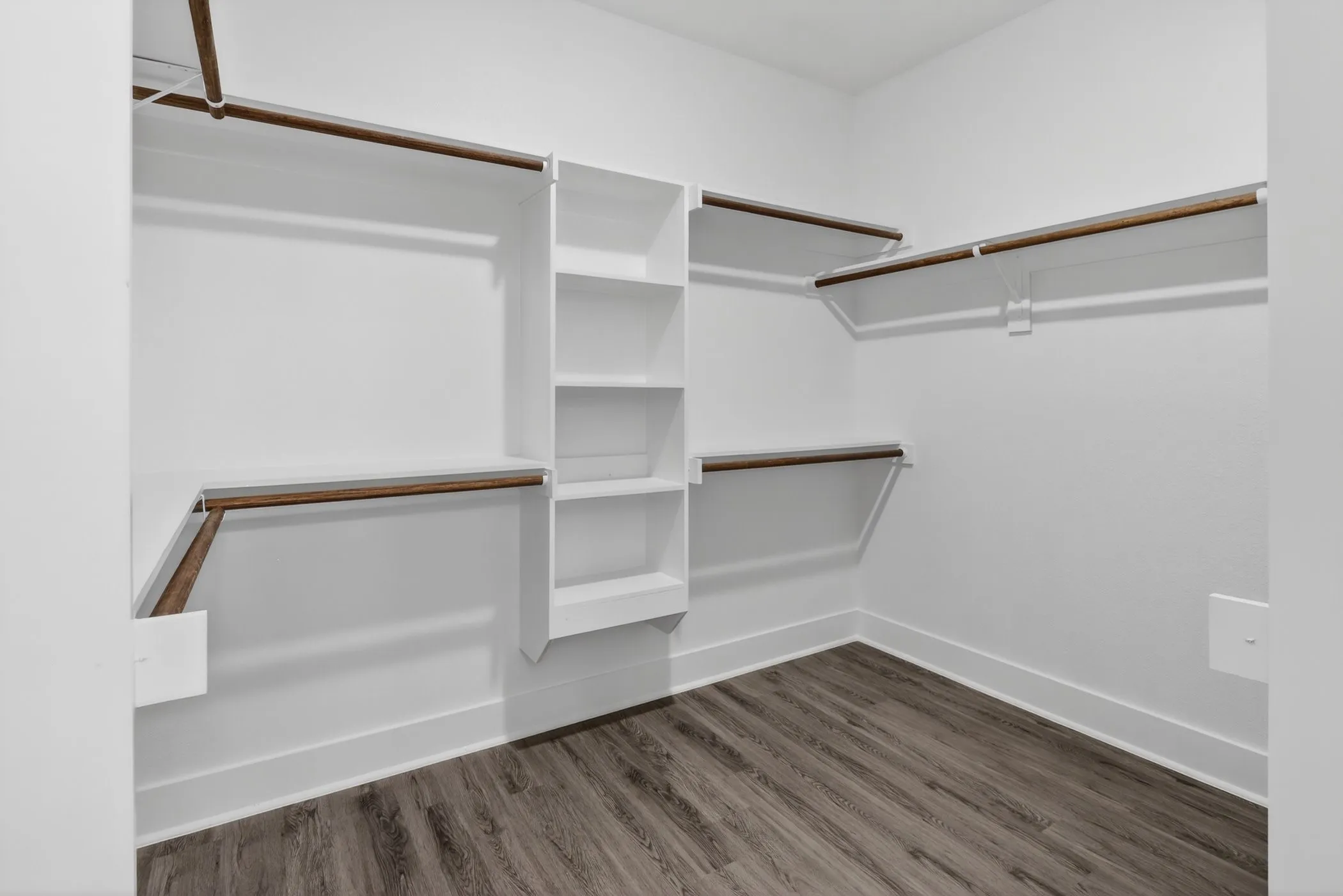 Walk-in closet with wood-finish flooring, white walls, and white baseboards