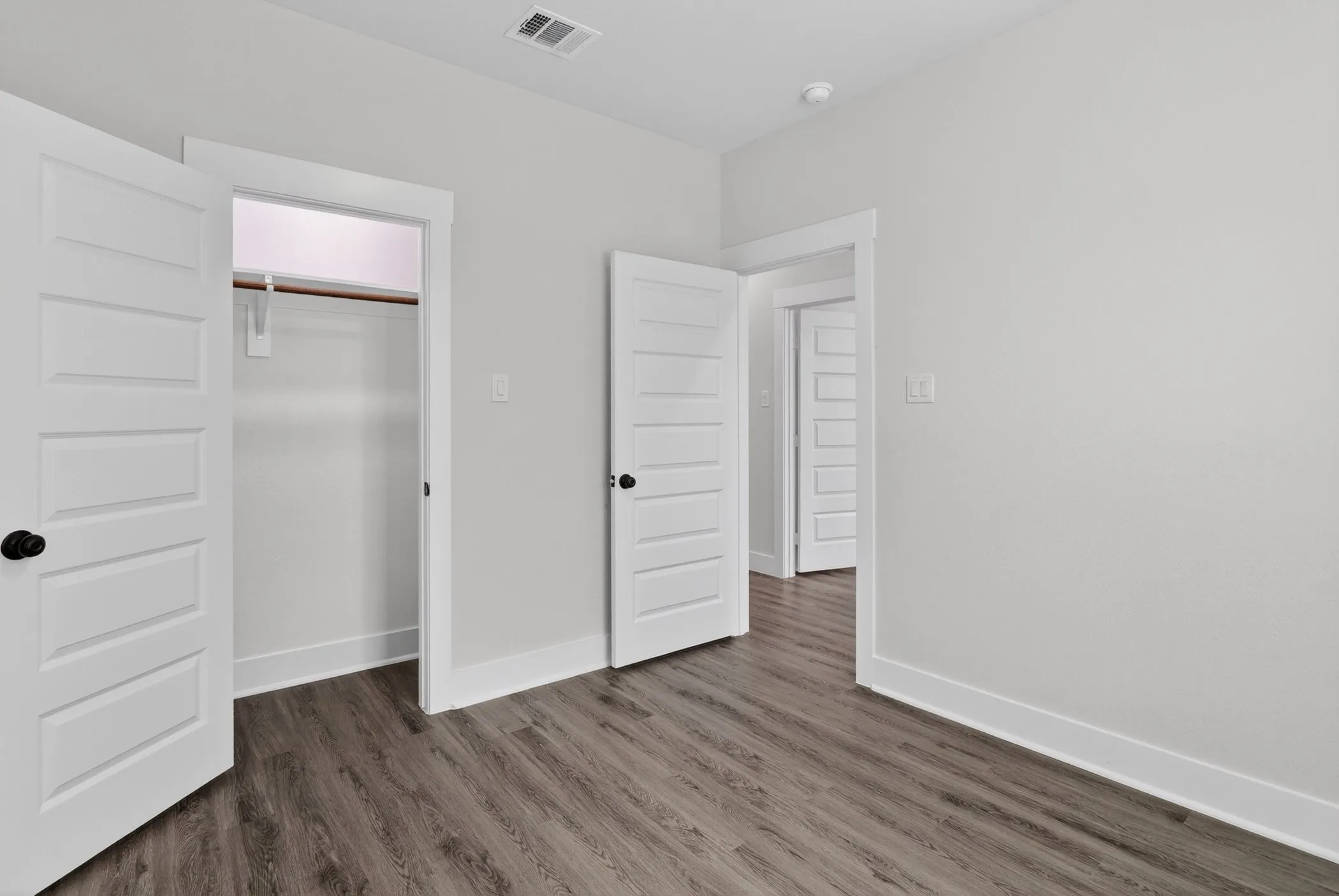 Interior room featuring wood-finish flooring, white walls, and a window with blinds