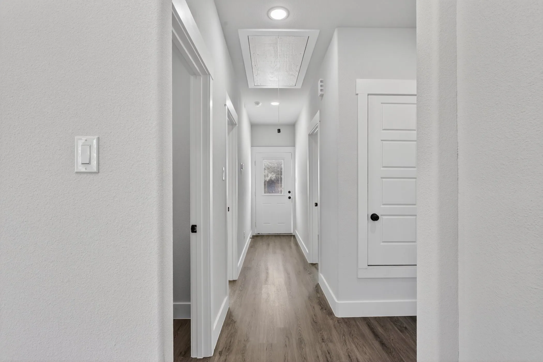 Hallway featuring wood-finish flooring, recessed lighting, and crisp white trim