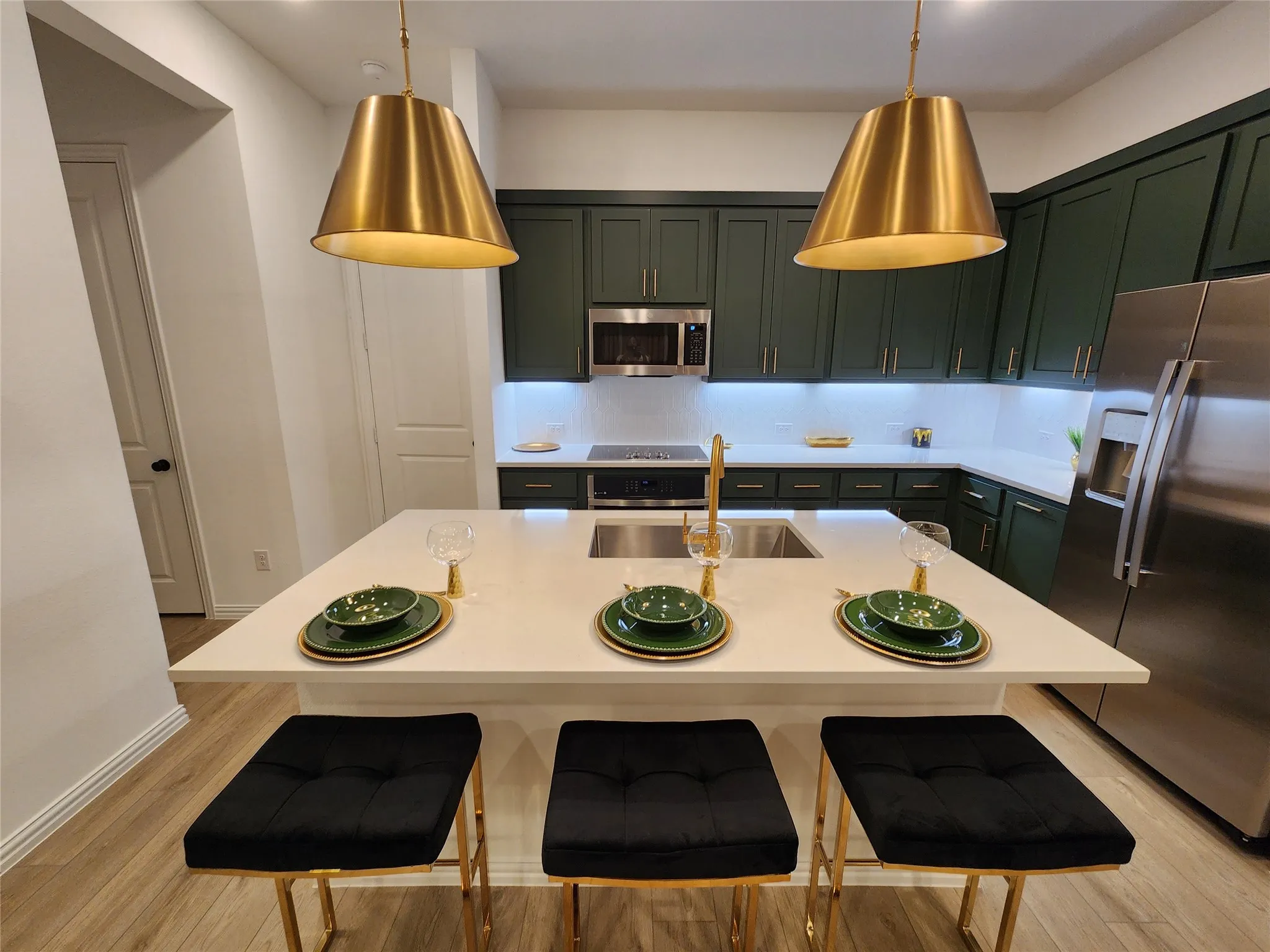 Kitchen with stainless steel appliances, a breakfast bar, light wood finished floors, and an island with sink
