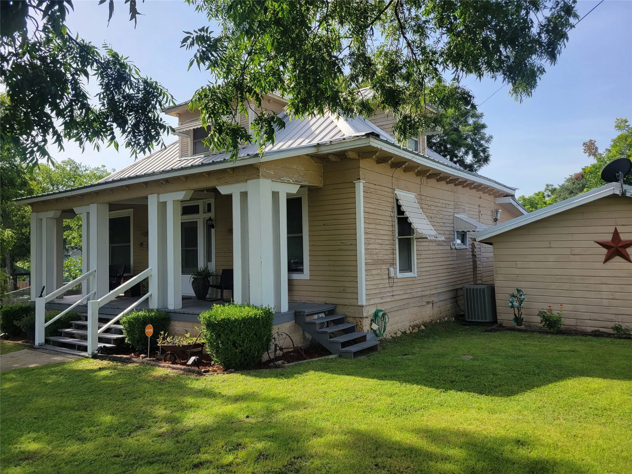 View of side of home featuring covered porch, a yard, and a metal roof