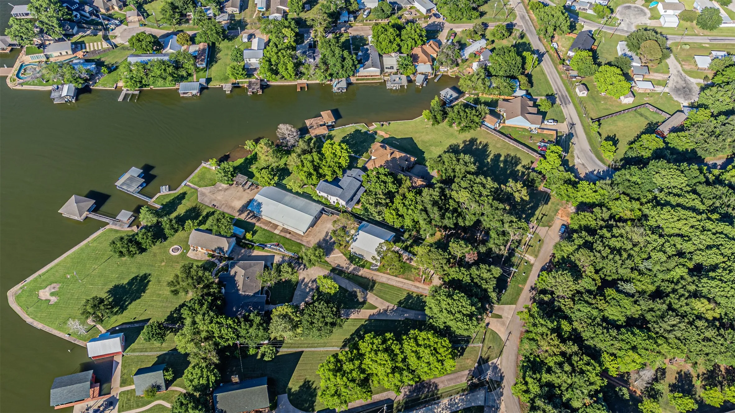Waterfront property featuring multiple structures, mature trees, and direct water access with boat docks
