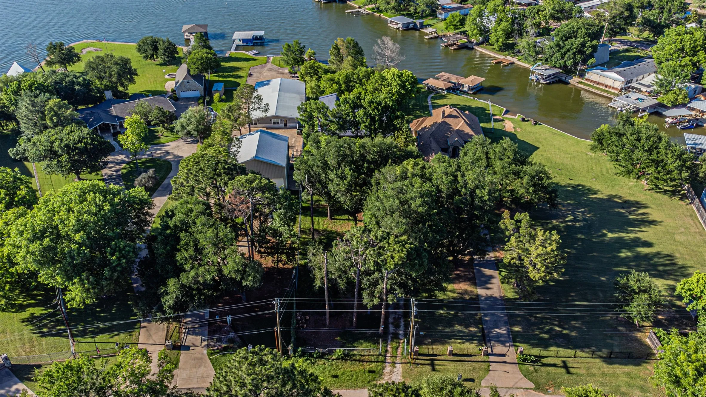Waterfront property featuring an expansive green lawn and mature trees