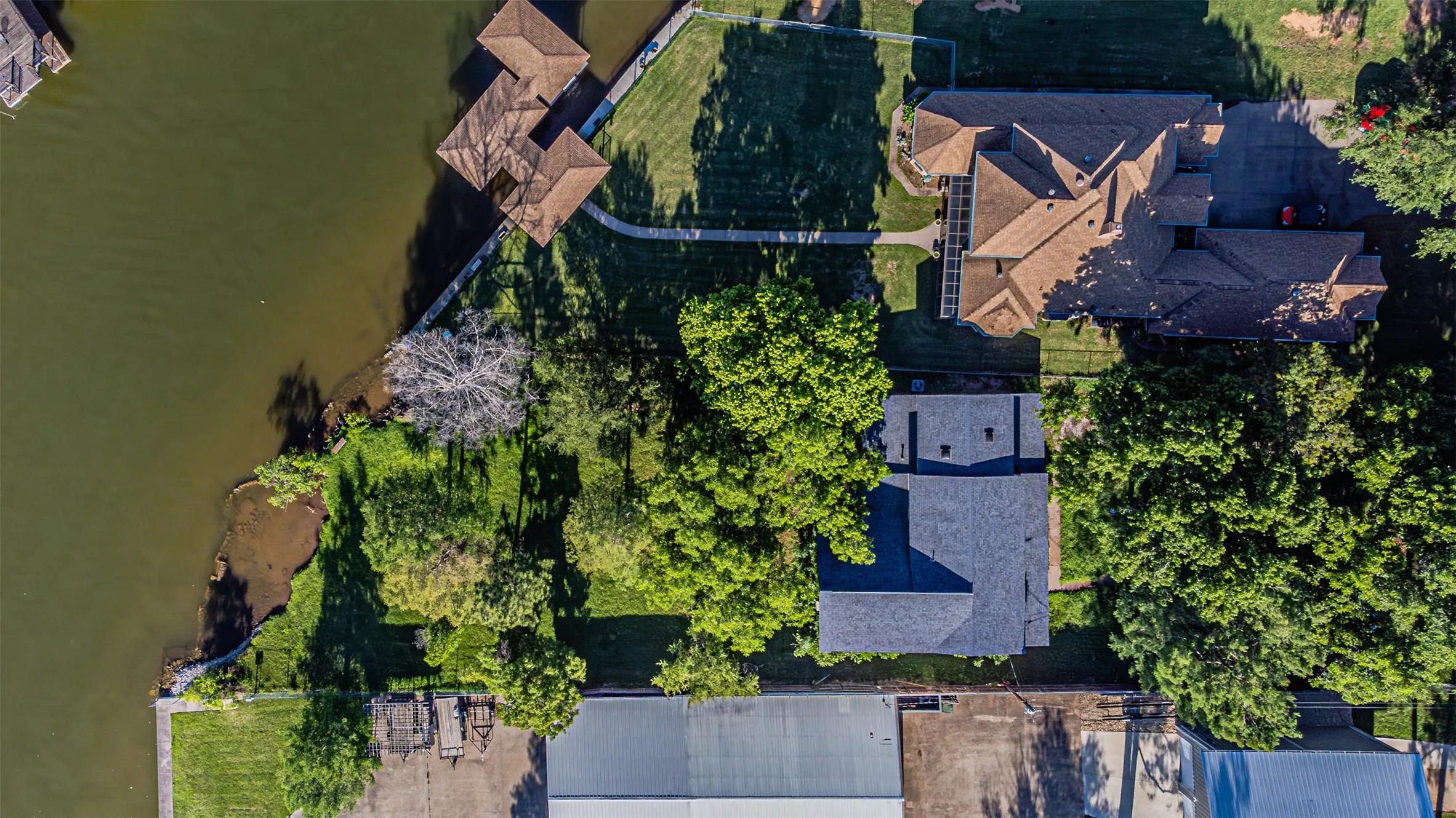 Waterfront property with private dock facilities, a spacious main residence featuring a multi-gabled roofline, and extensive green space